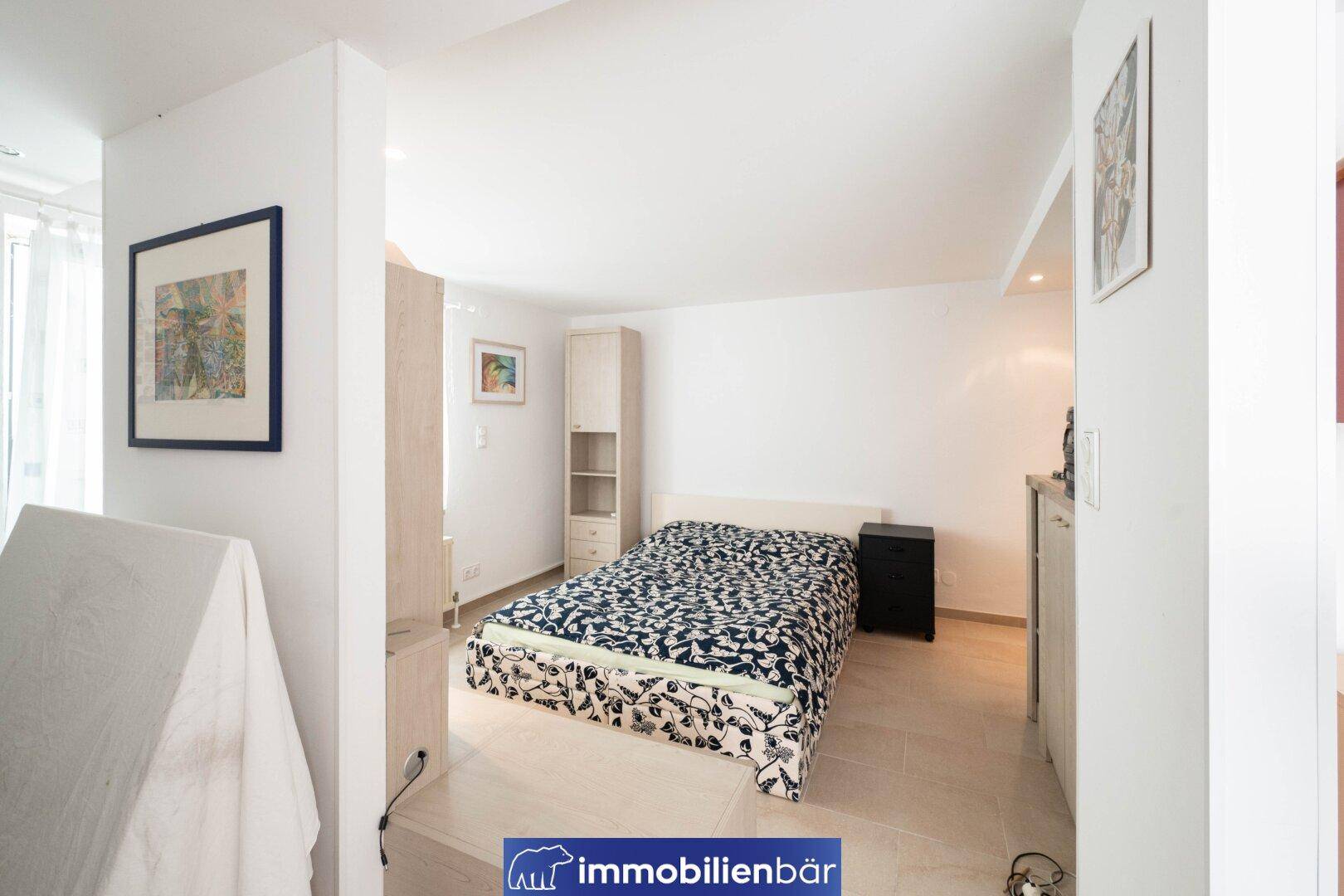 Schlafzimmer mit Einzelbett, Schrank und Fliesenboden im Untergeschoss des Hauses.