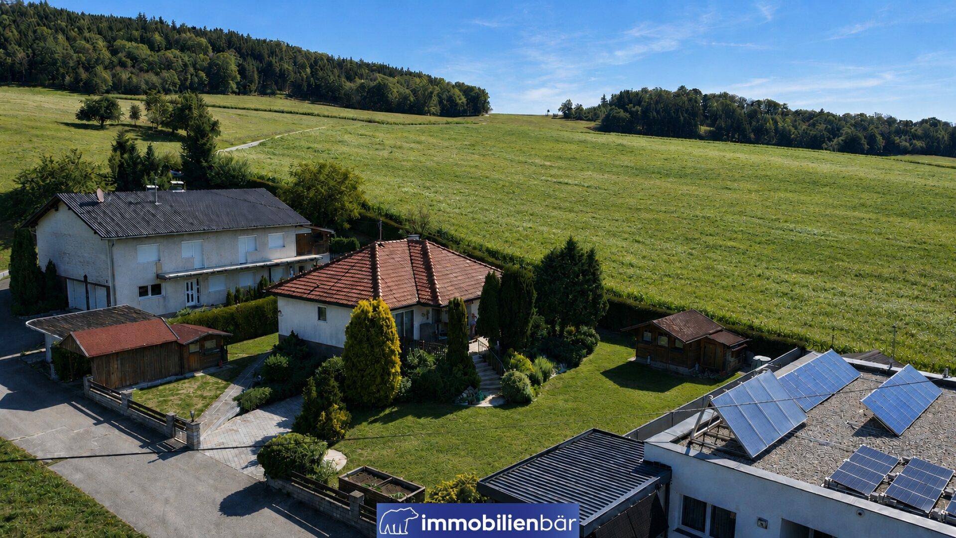 Luftaufnahme des Hauses mit Garten, umgeben von grünen Feldern und Wäldern, mit Fernblick.