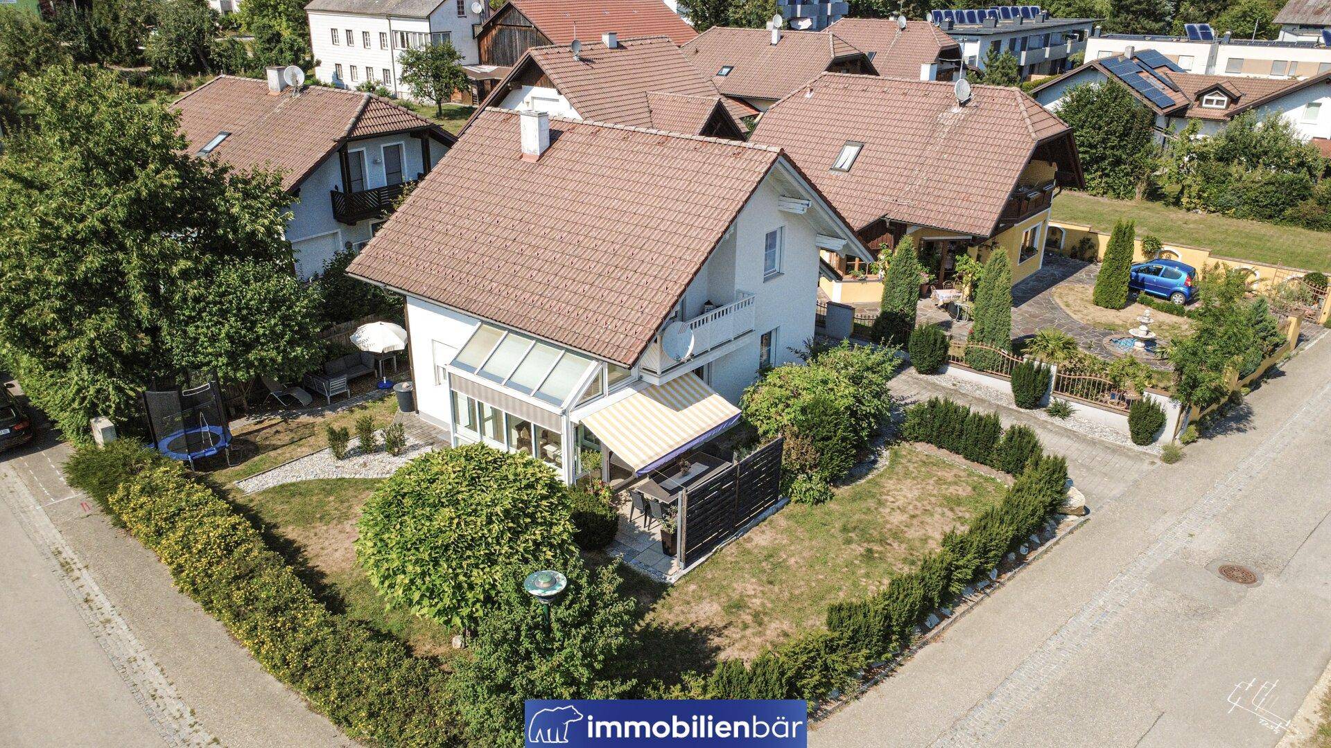 Luftaufnahme des Hauses mit Wintergarten, Garten und Trampolin im Außenbereich.