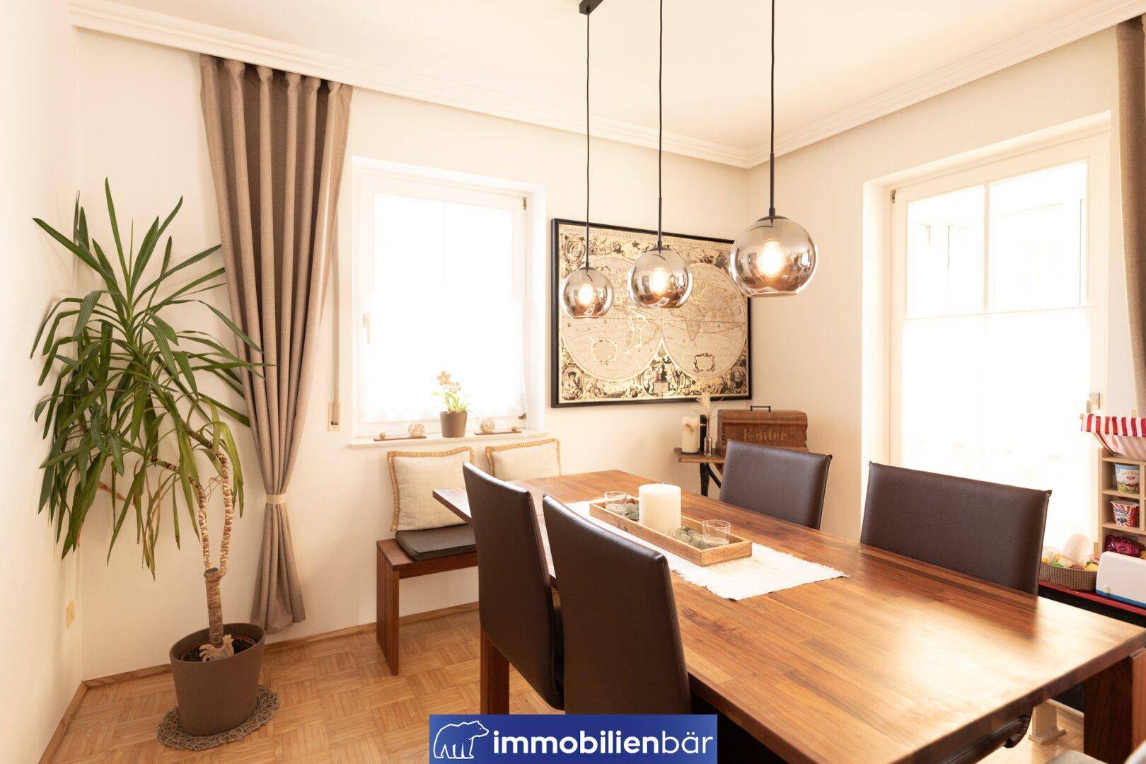 Gemütlicher Essbereich mit Holztisch, modernen Pendelleuchten und Blick ins Grüne.