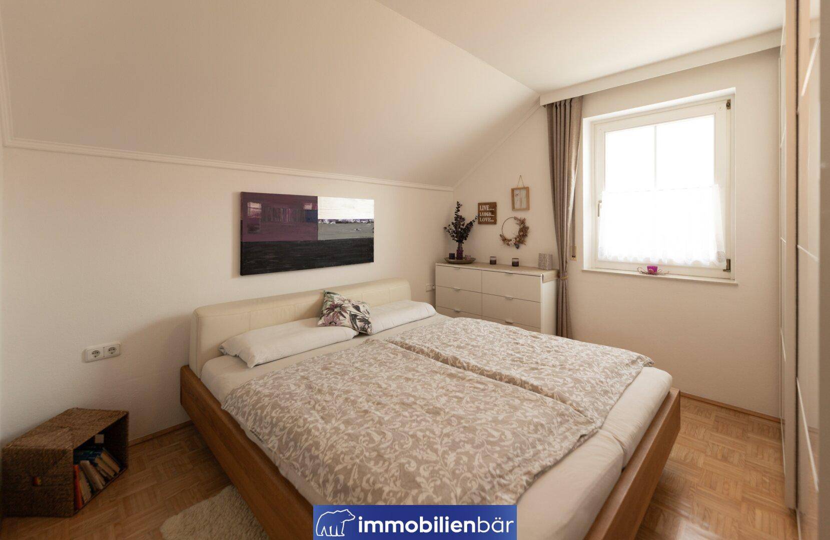 Geräumiges Schlafzimmer mit Doppelbett, Kommode und Fenster im Dachgeschoss.