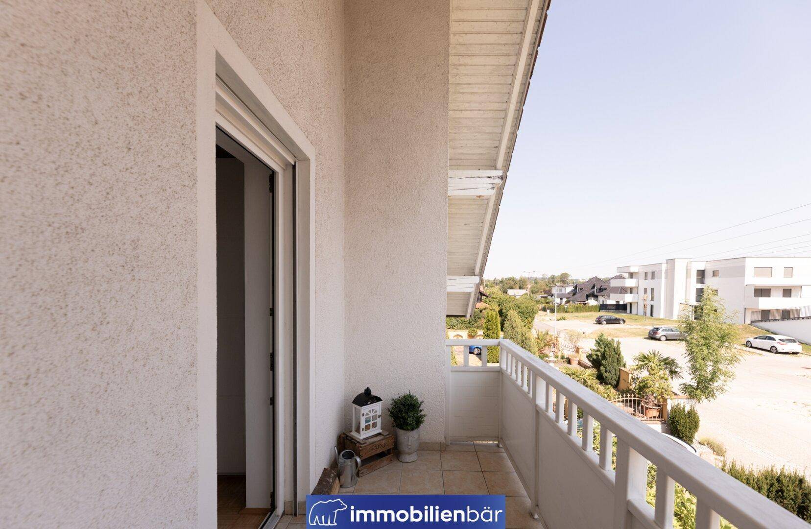 Kleiner Balkon mit weißem Geländer und Blick auf die umliegende Wohngegend.