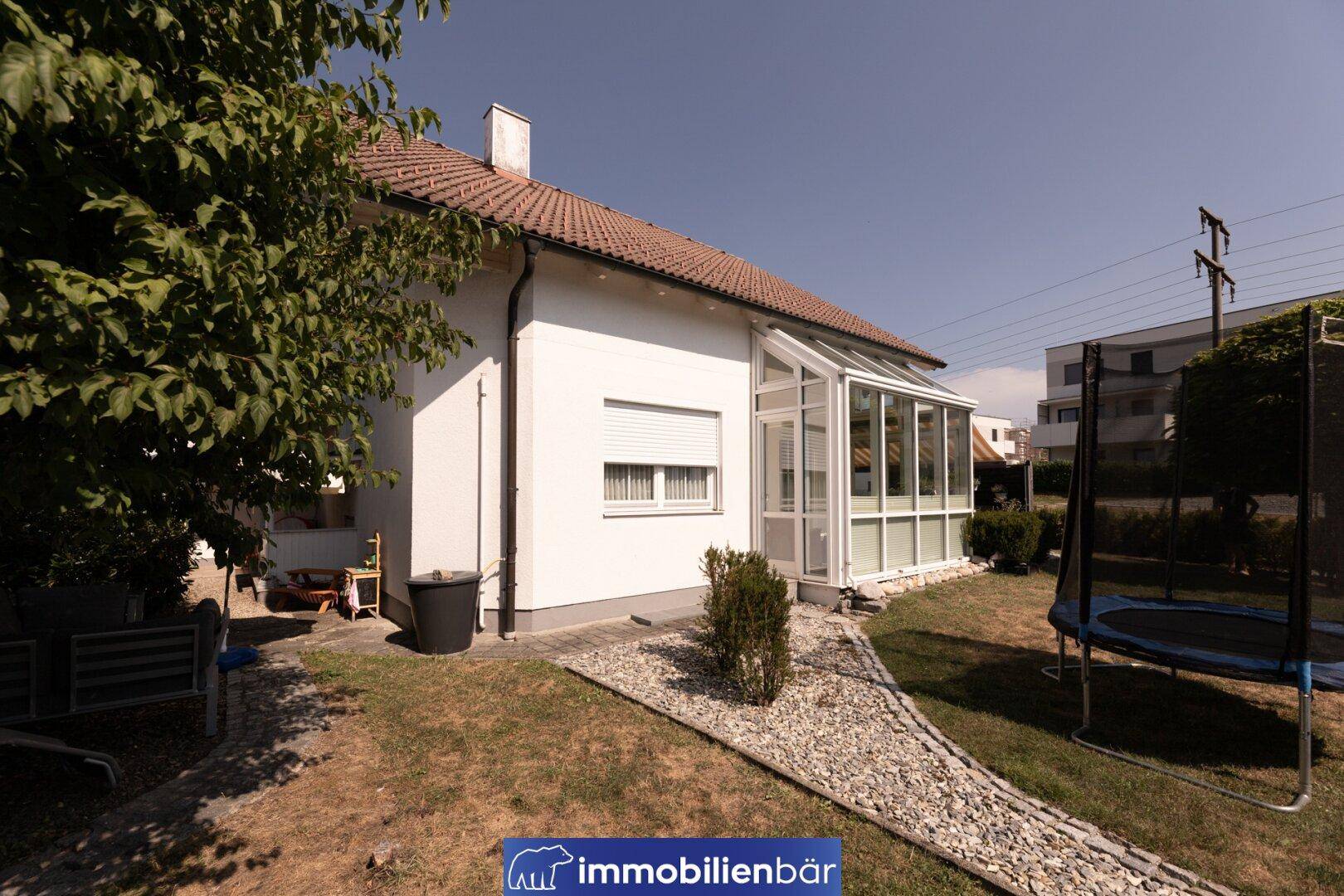 Seitenansicht des Hauses mit Wintergarten und einem Trampolin im Garten.