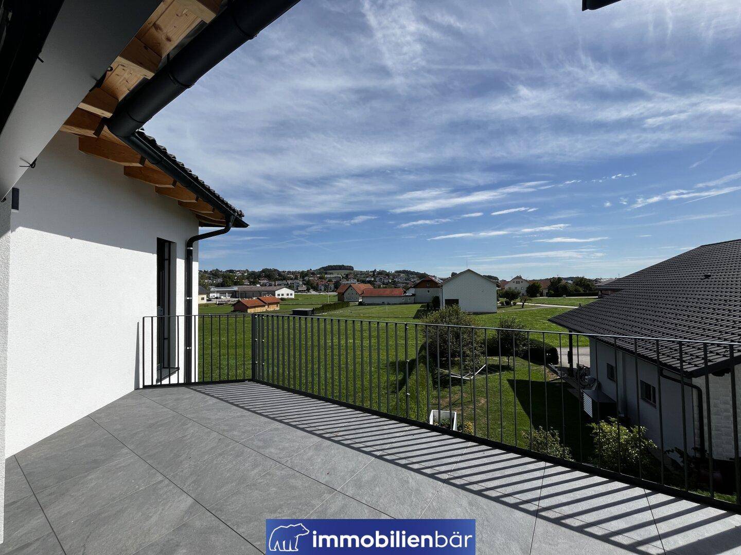 Großer Balkon mit Fliesenboden und weitem Blick über die grüne Landschaft.