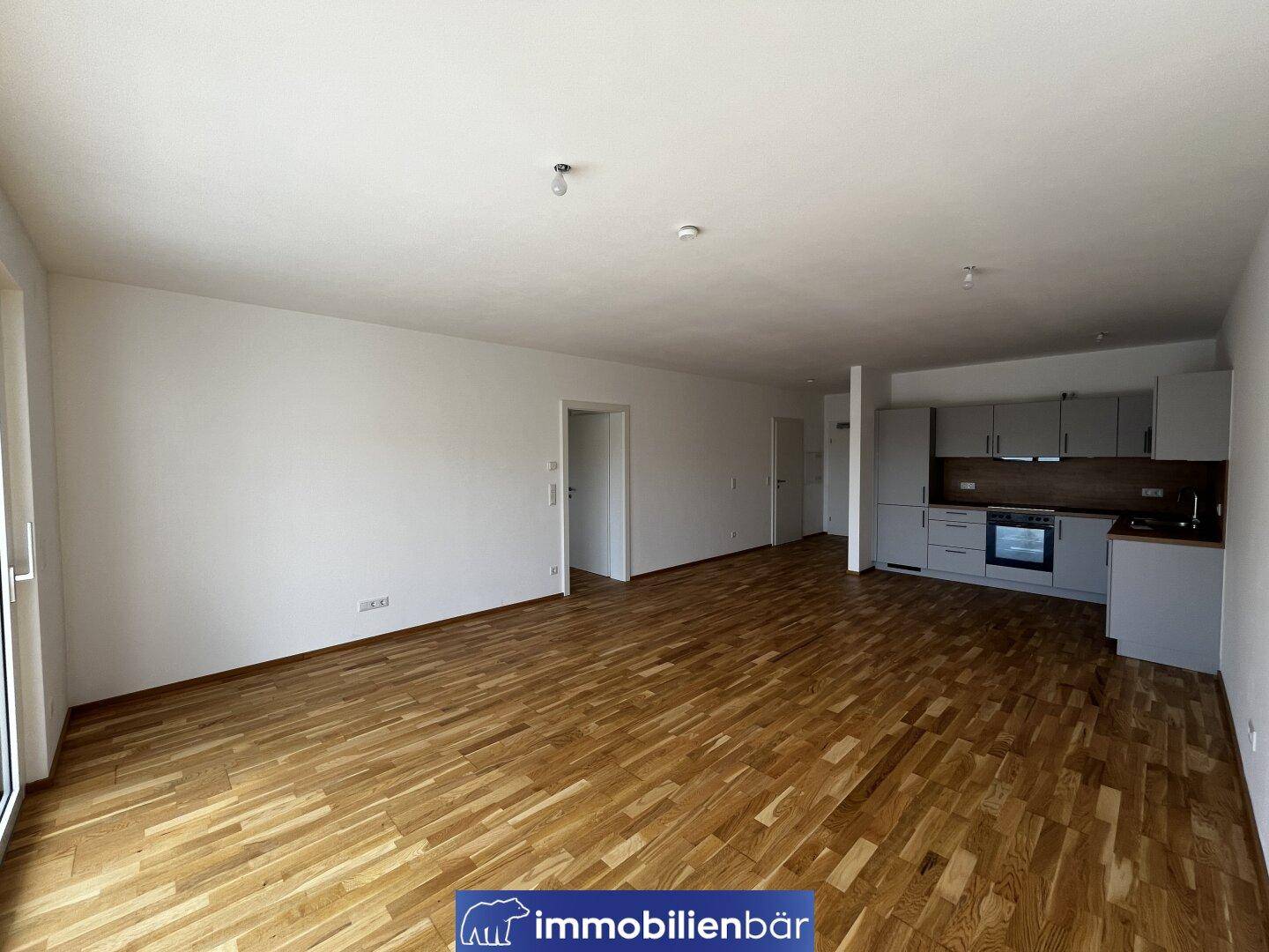 Heller Wohn- und Essbereich mit moderner Küchenzeile und hochwertigem Holzfußboden.