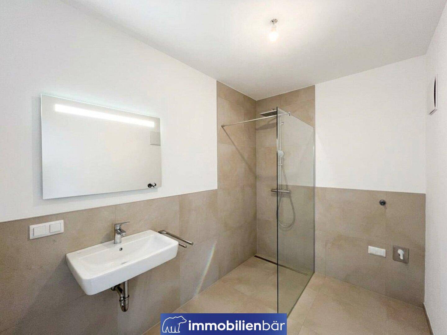 Modernes Badezimmer mit ebenerdiger Dusche, Einzelwaschbecken und hellen Fliesen.