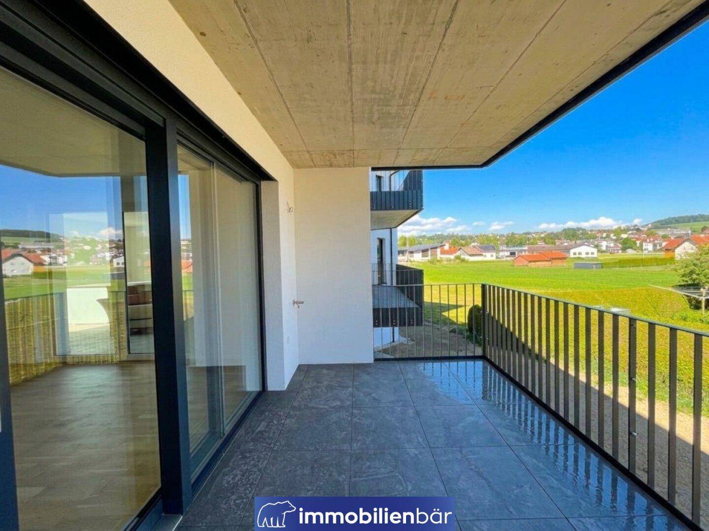 Geräumiger Balkon mit Fliesenboden und weitem Blick ins Grüne und die Umgebung.