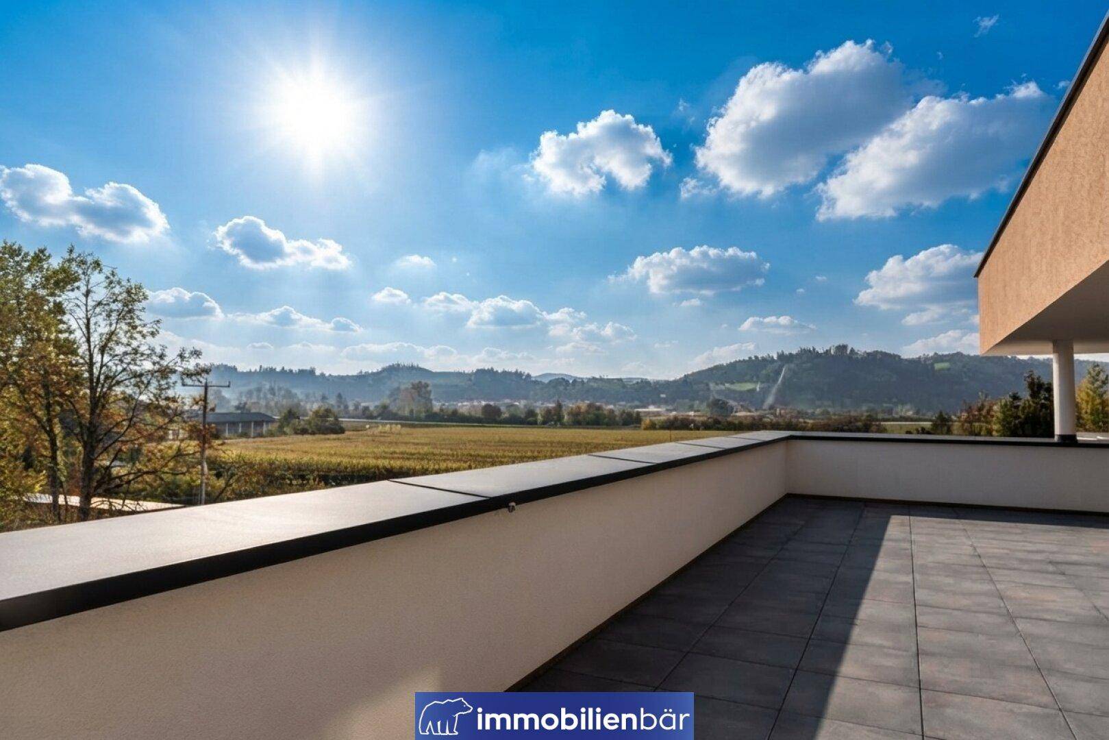 Sonnige Terrasse mit Fliesenboden und einem weiten Blick über die Landschaft und Weinberge.