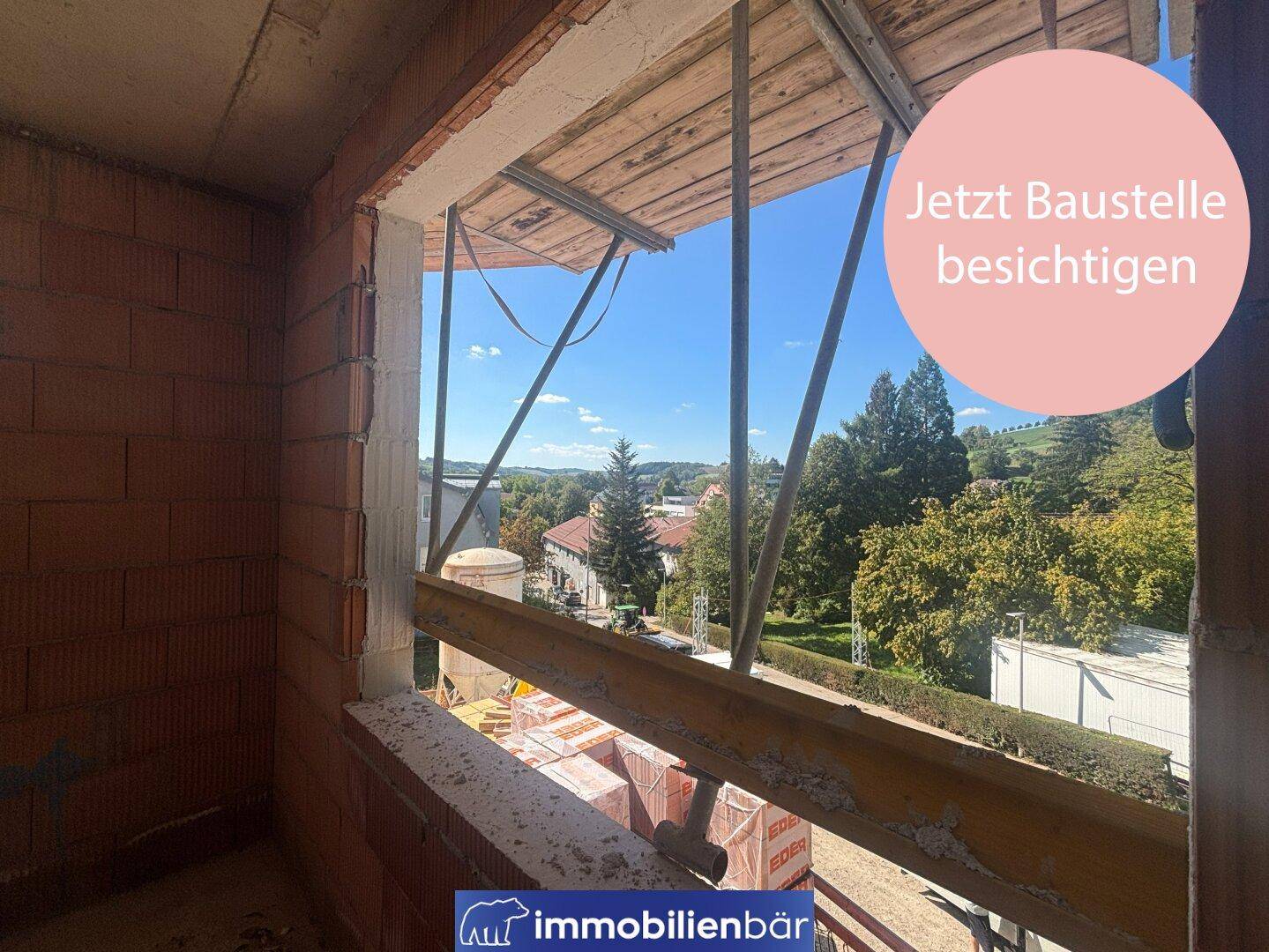 Innenansicht eines Raumes im Rohbau mit Blick auf die grüne Umgebung und das Dorf.