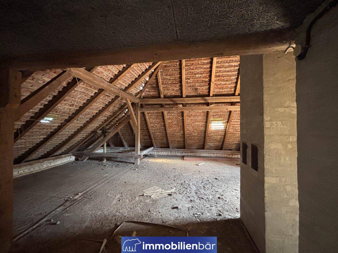 Ein unfertiger Dachboden mit sichtbaren Holzbalken und Ziegeln, der viel Potenzial bietet.