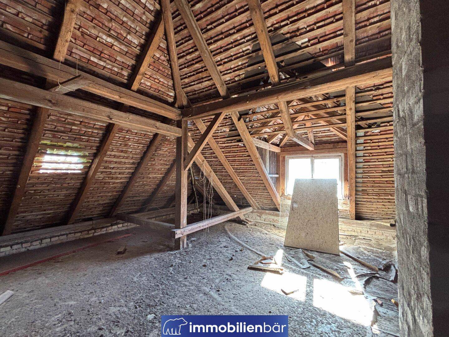Ein geräumiger Dachboden mit freiliegenden Holzbalken und einem kleinen Fenster, das Licht spendet.