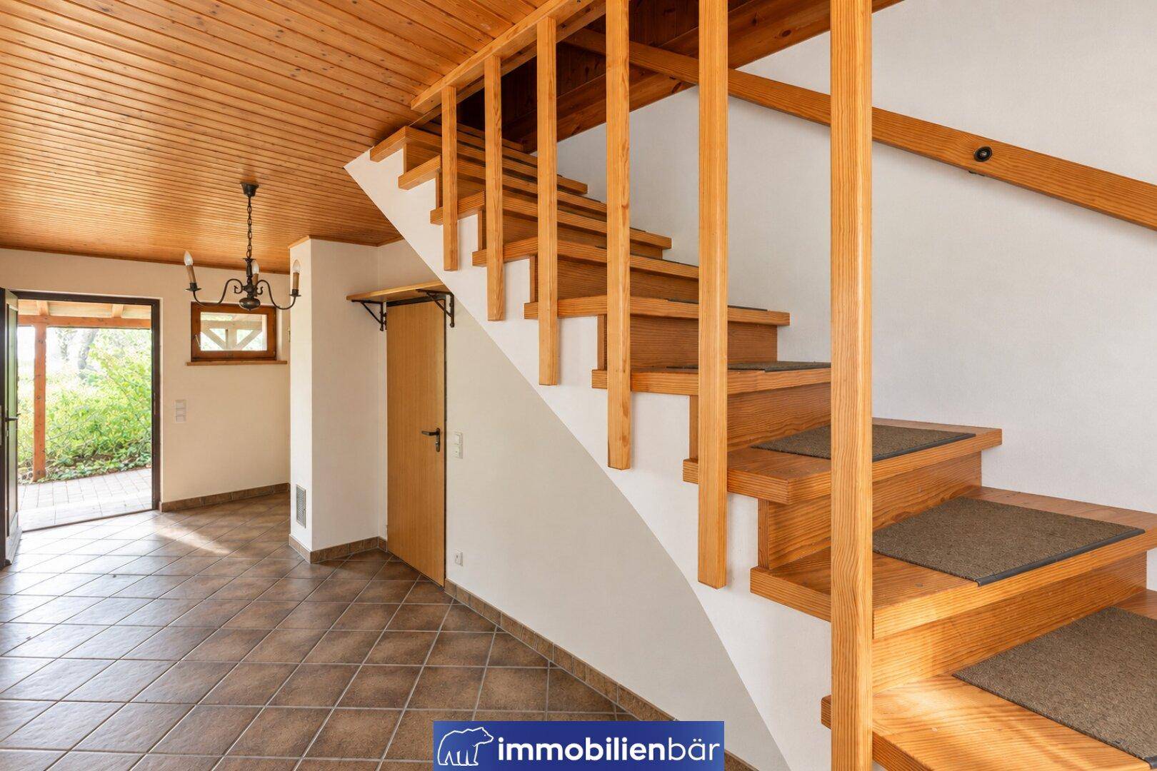 Eingangsbereich mit Holztreppe und Fliesenboden, führt in die oberen Etagen des Hauses.