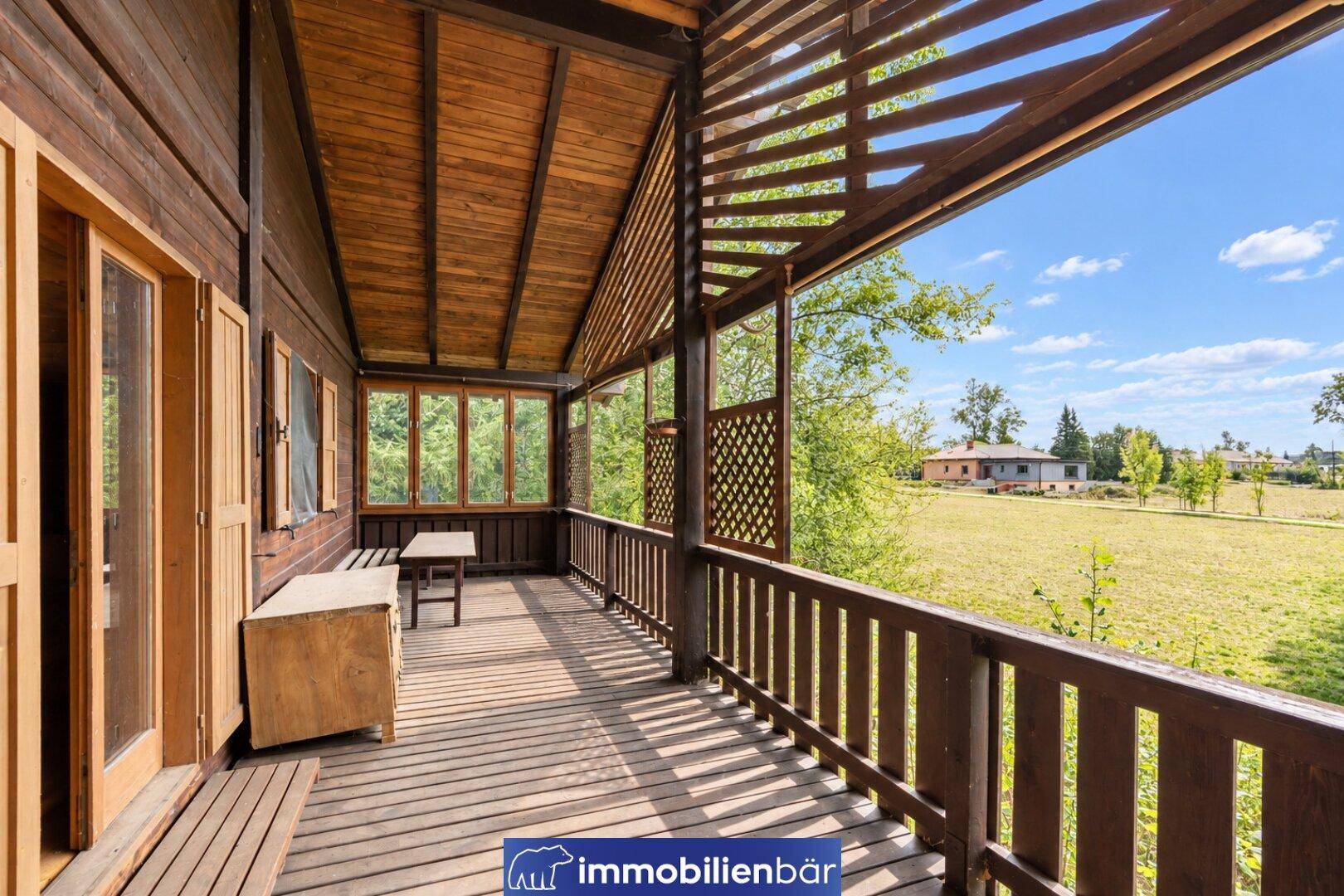 Geräumiger Holzbalkon mit rustikalem Geländer und weitem Blick über die grüne Landschaft.