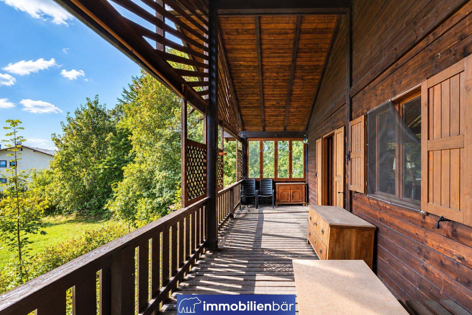 Langer Holzbalkon mit rustikalem Geländer und weitem Blick über die grüne Landschaft.