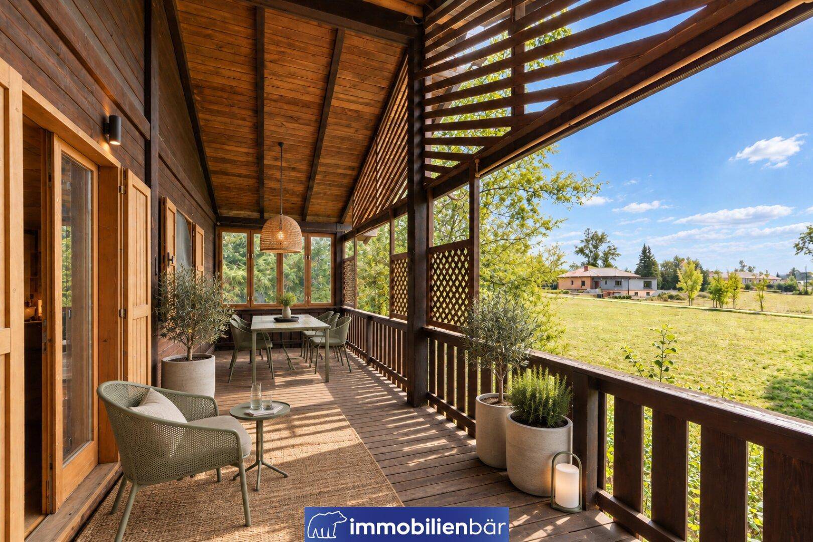 Einladender Holzbalkon mit Sitzgelegenheiten und Pflanzen, bietet einen weiten Blick ins Grüne.