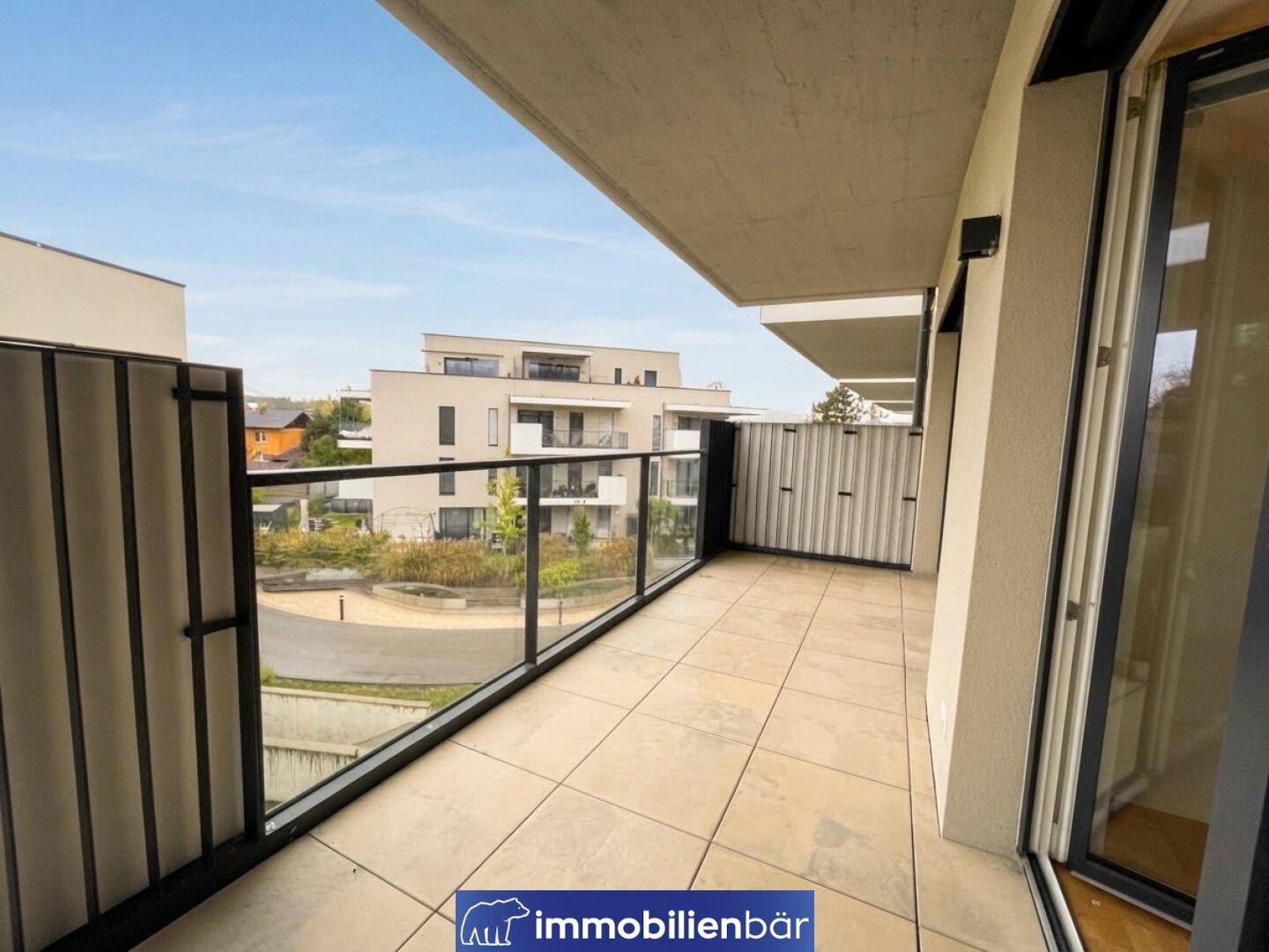 Langer Balkon mit Fliesenboden und Glasgeländer, bietet einen weiten Blick auf die Umgebung.