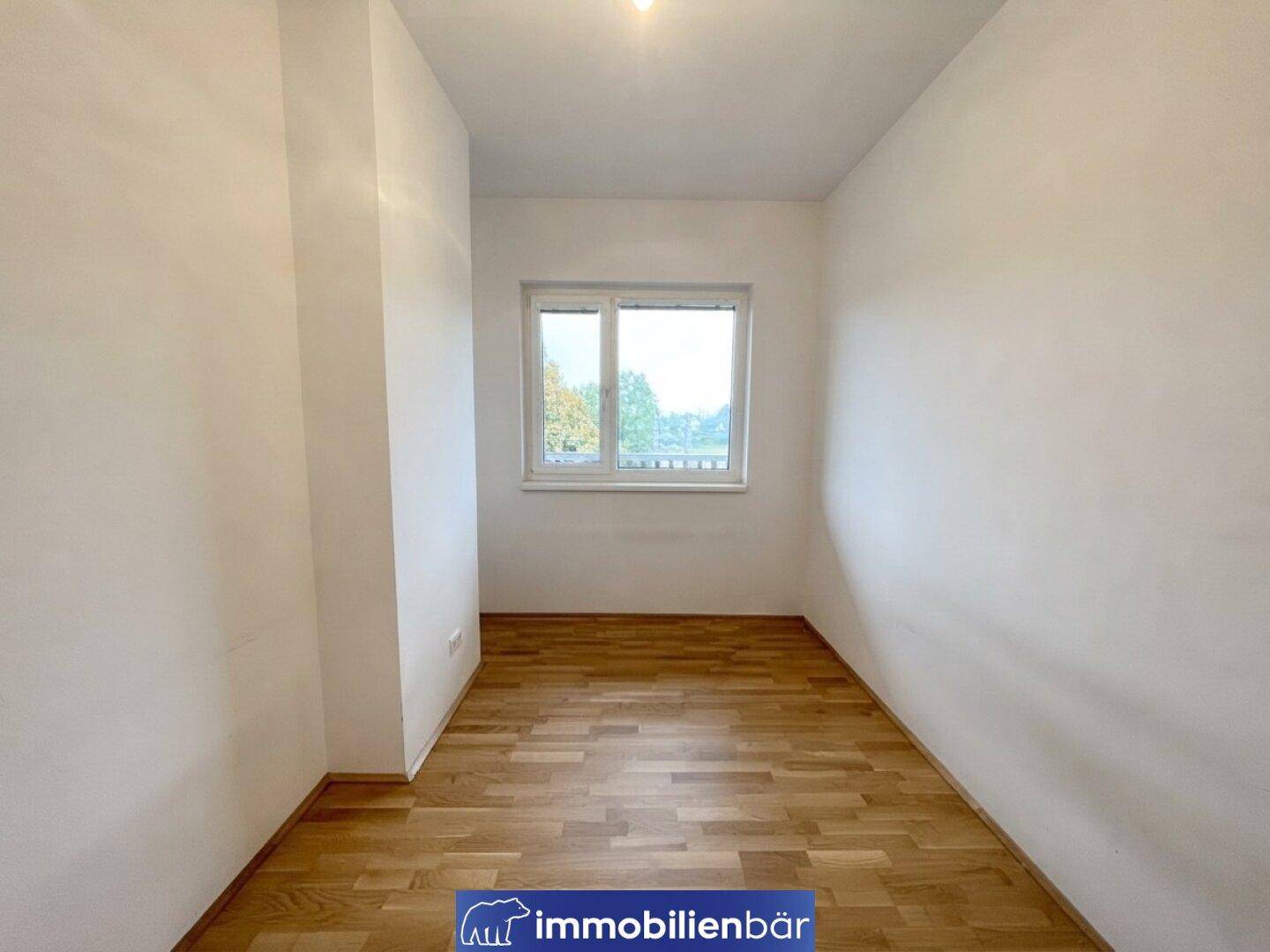 Kleineres Zimmer mit Parkettboden und einem Fenster, das Tageslicht hereinlässt.