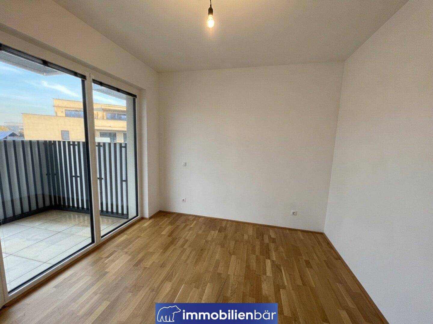 Unmöblierter Raum mit Parkettboden und Zugang zu einem Balkon, ideal für individuelle Gestaltung.