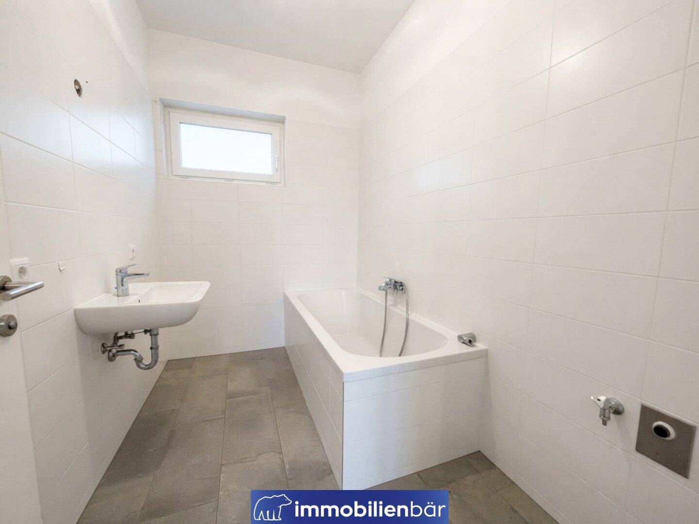 Modernes Badezimmer mit Badewanne, Waschbecken und weißen Fliesen an den Wänden.