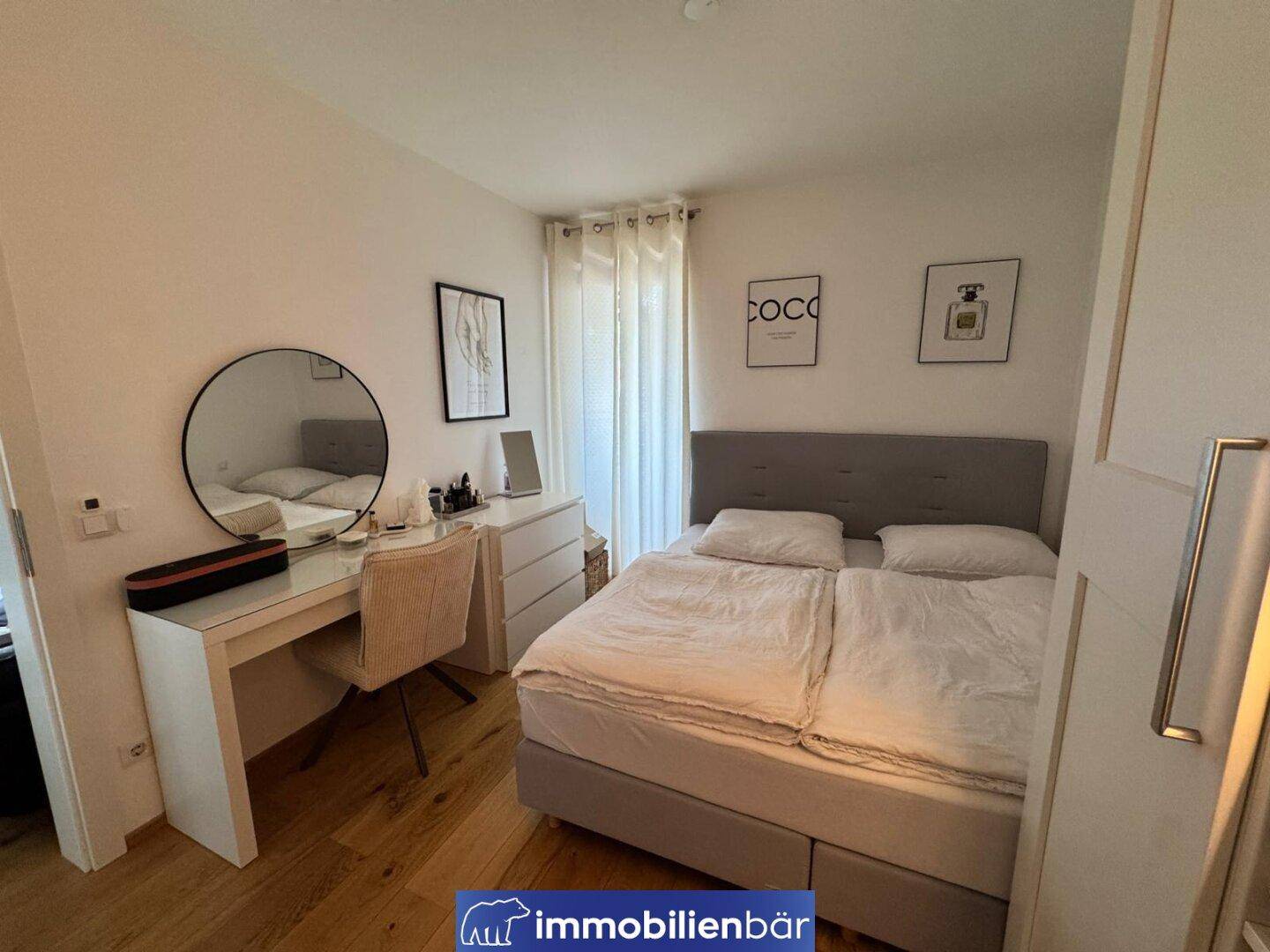 Helles Schlafzimmer mit Doppelbett, modernem Schminktisch und Holzboden.
