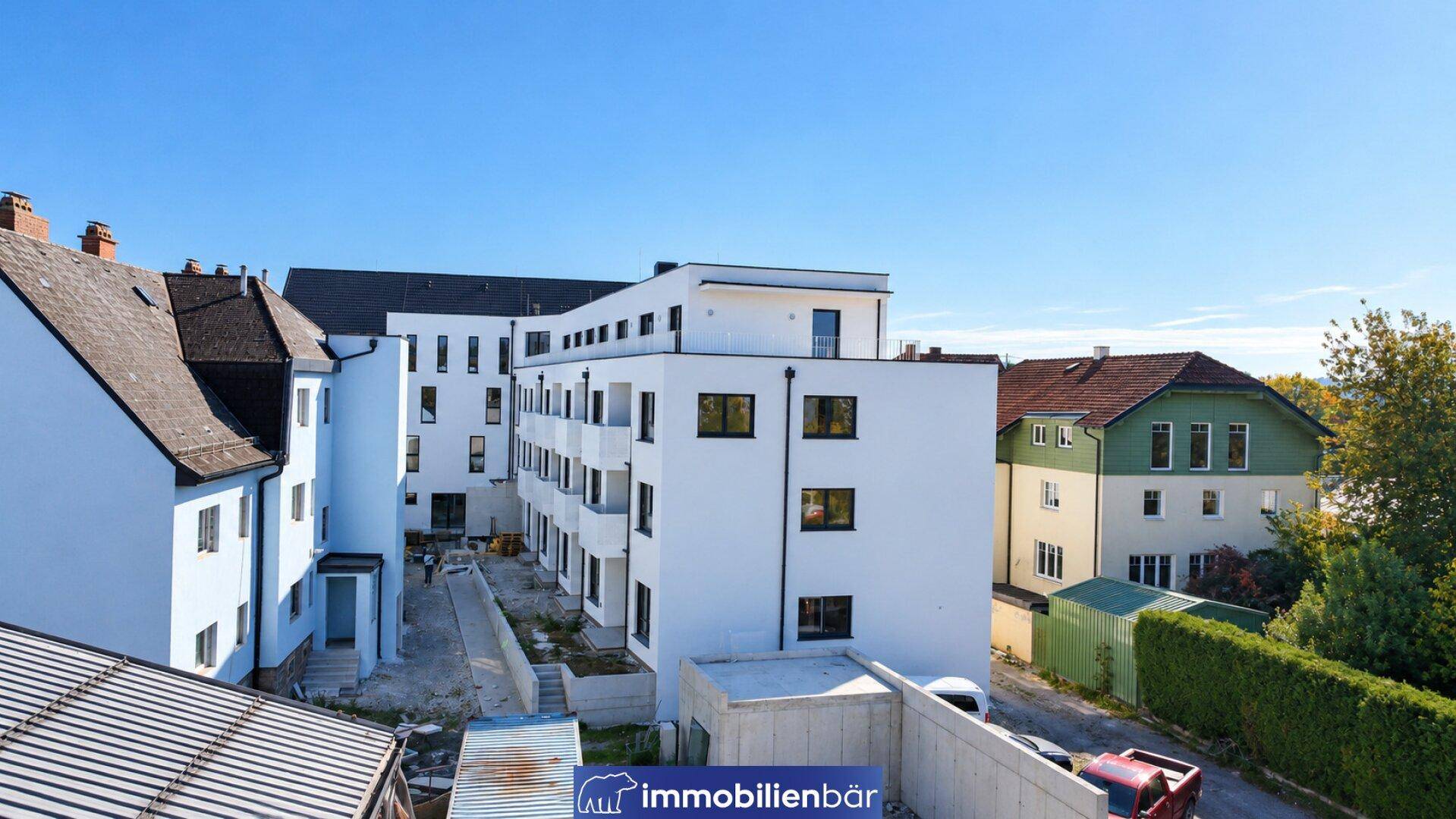 Rückansicht des Neubaus mit Innenhof und angrenzenden traditionellen Gebäuden.