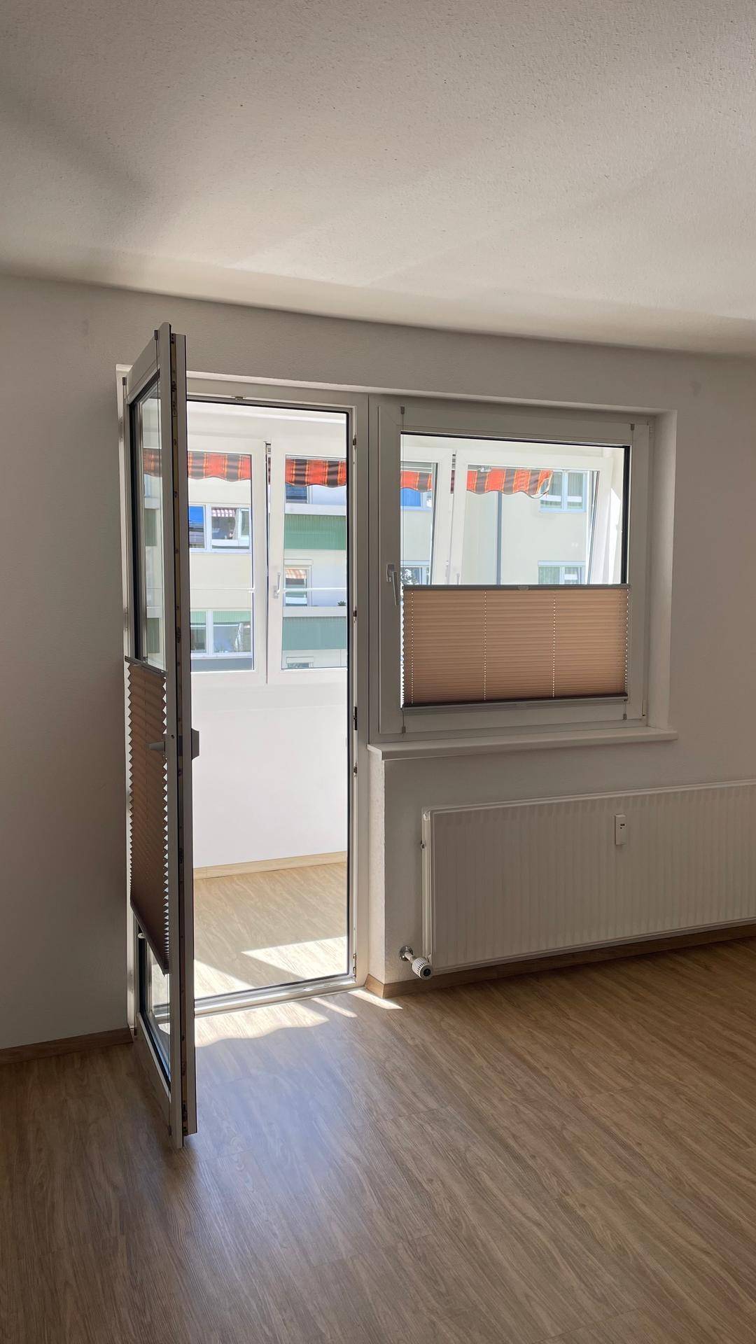 Heller Raum mit Zugang zu einem Balkon oder einer Loggia und Blick nach draußen.