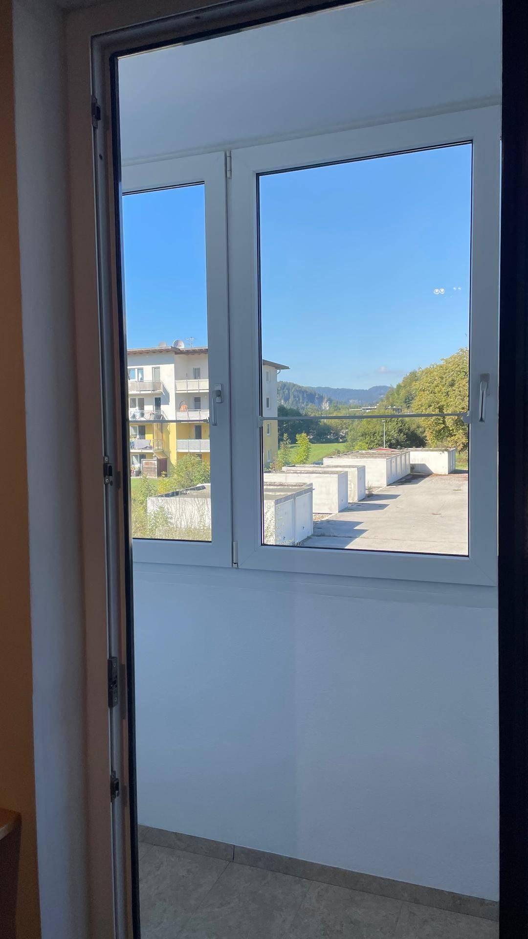 Blick aus einem Zimmer durch eine Tür auf einen Balkon mit Fernsicht auf die Landschaft.