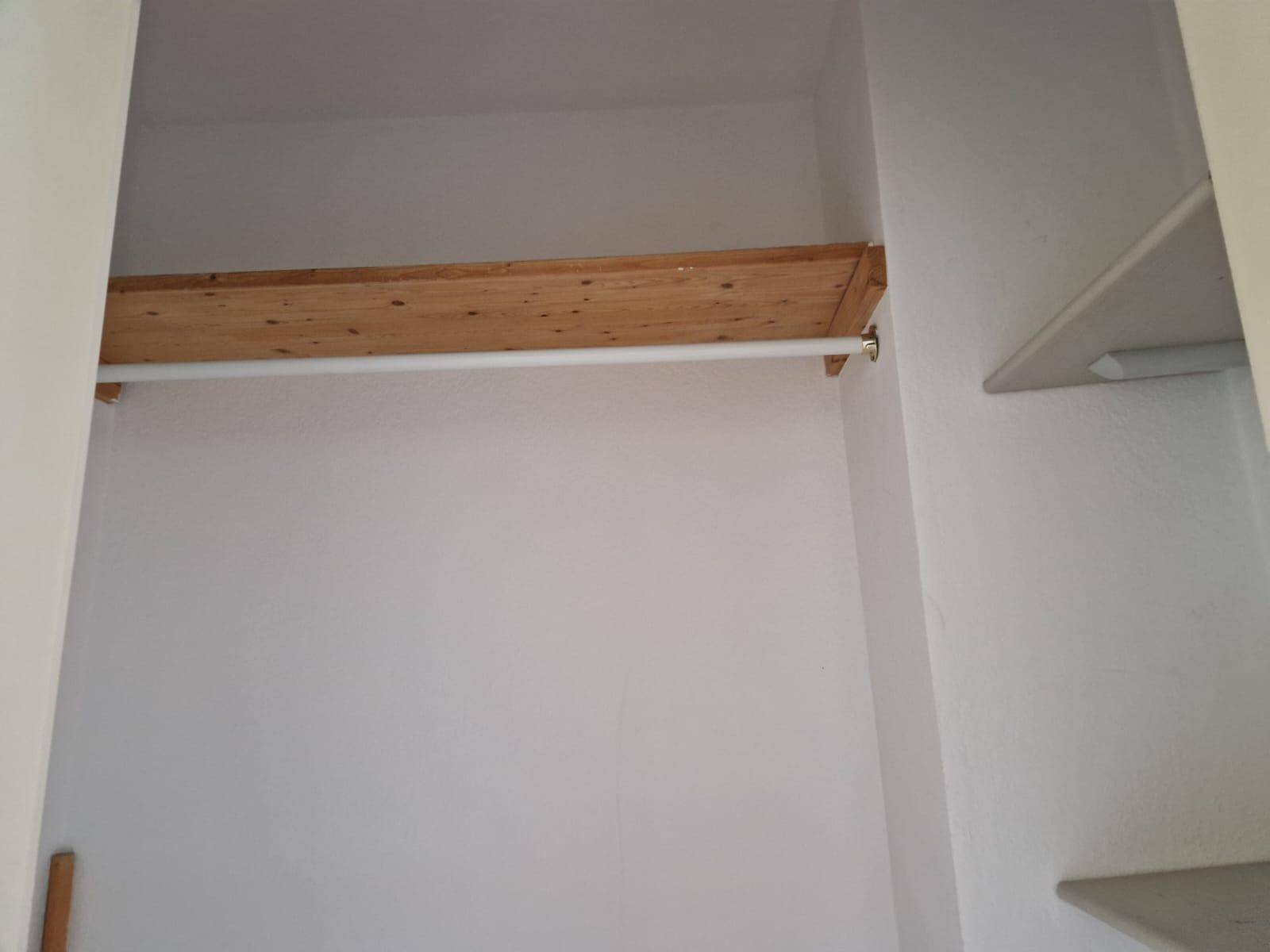 Einfacher Einbauschrank mit Kleiderstange und Regalbrett für zusätzlichen Stauraum.