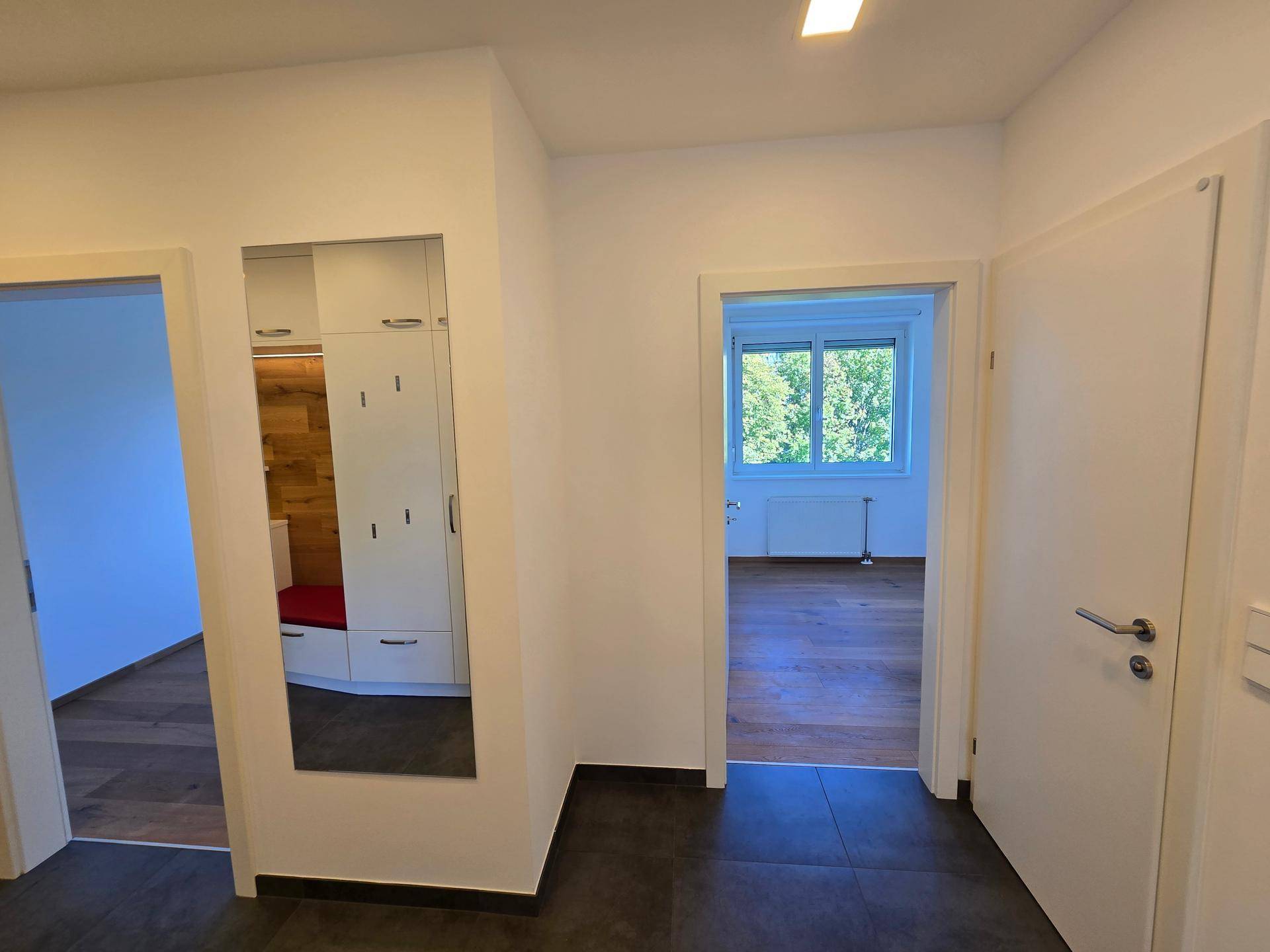 Geräumiger Flur mit dunklem Fliesenboden und Zugang zu mehreren Zimmern.