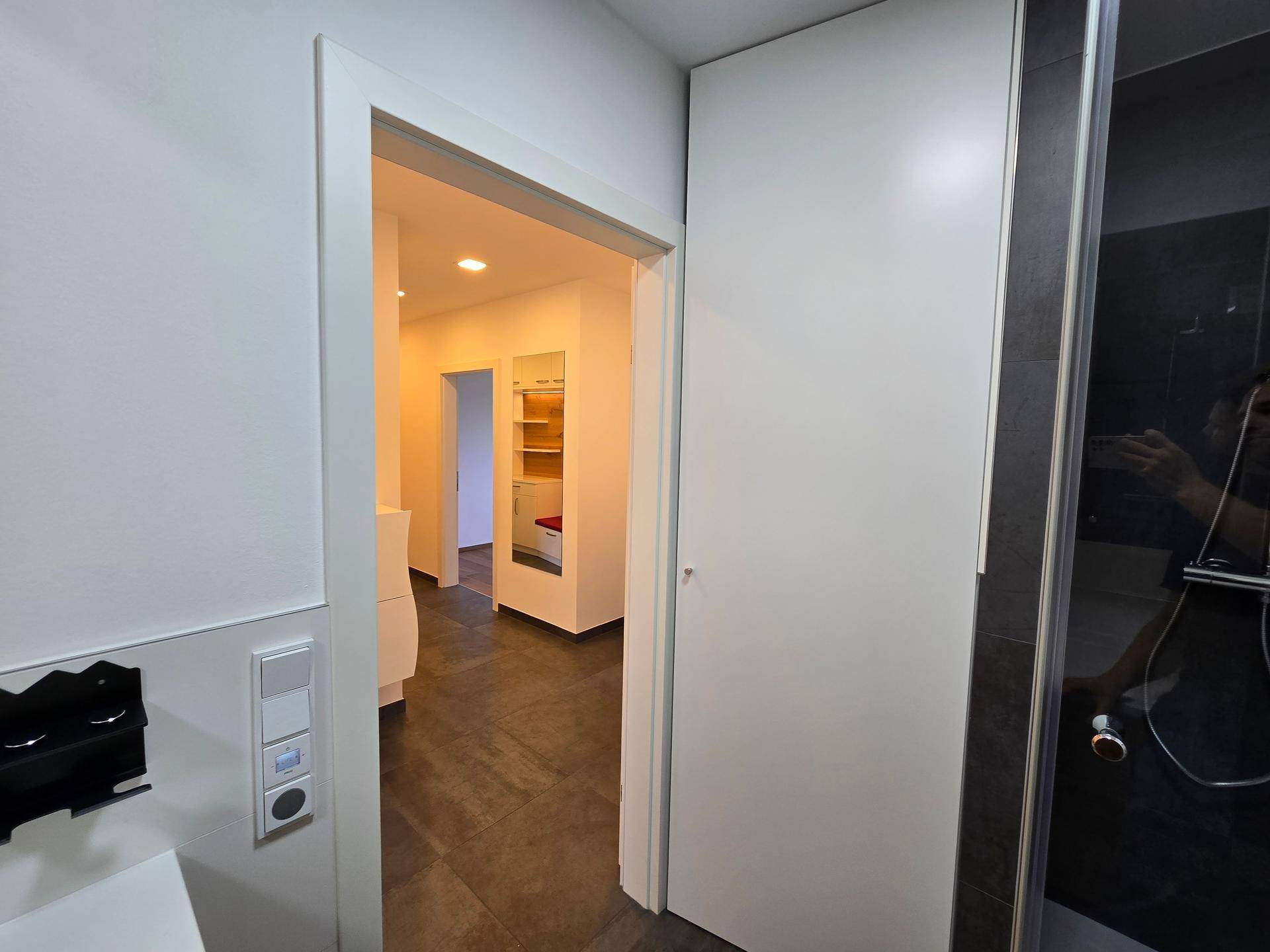 Blick aus dem Badezimmer in einen hellen Flur mit moderner Einrichtung.