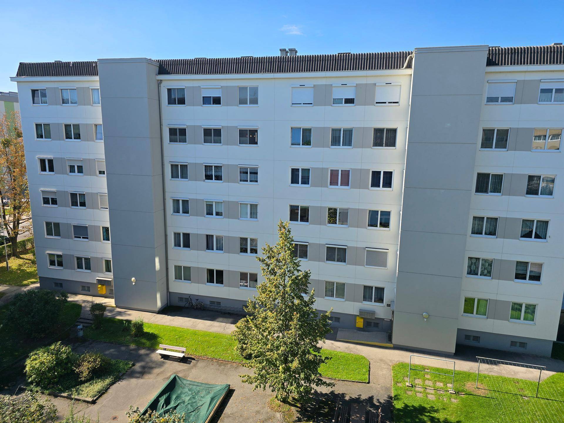 Ansicht eines Mehrfamilienhauses mit vielen Fenstern und gepflegten Grünflächen.
