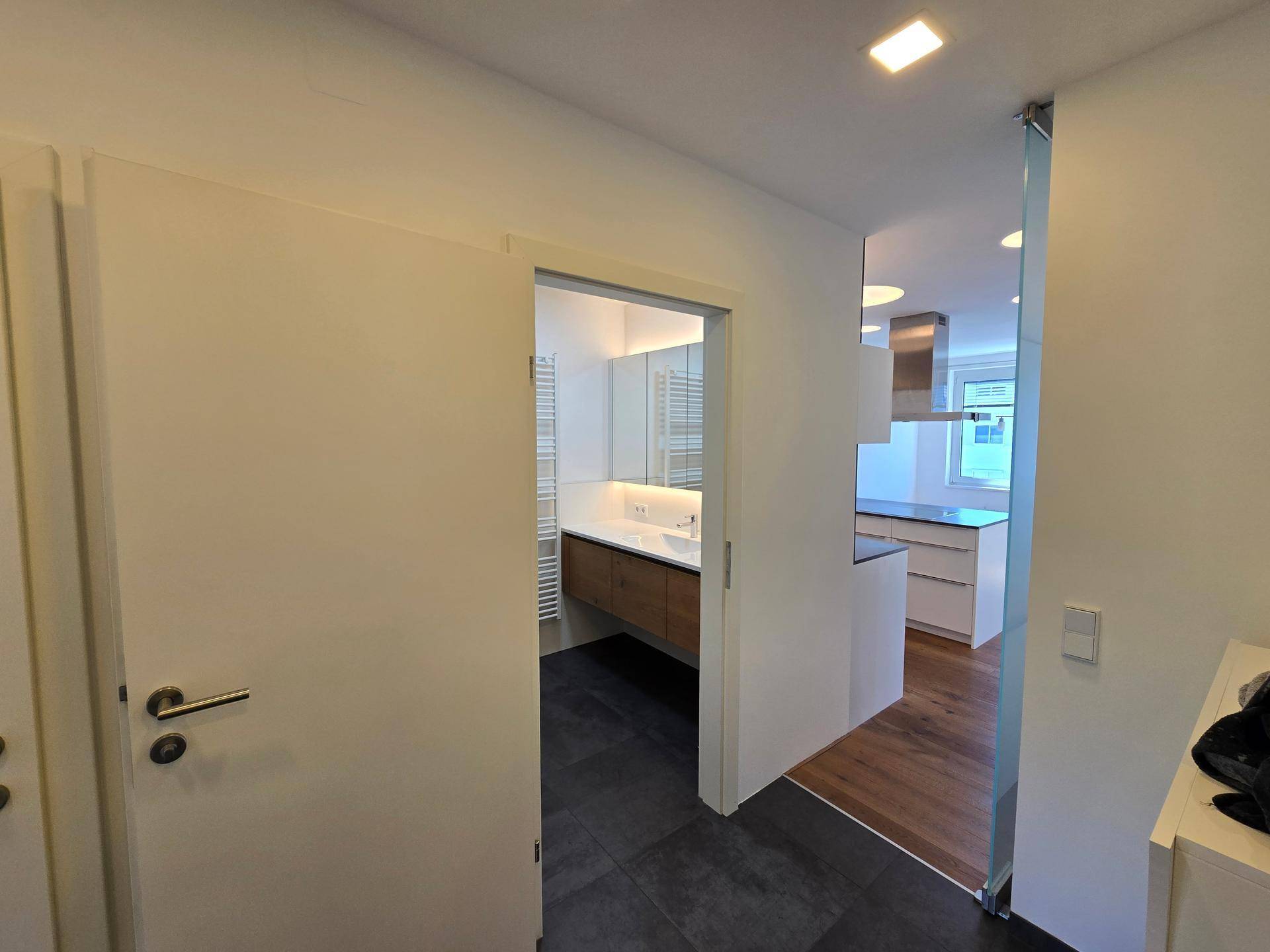 Flur mit Blick auf das moderne Badezimmer und den offenen Küchenbereich.