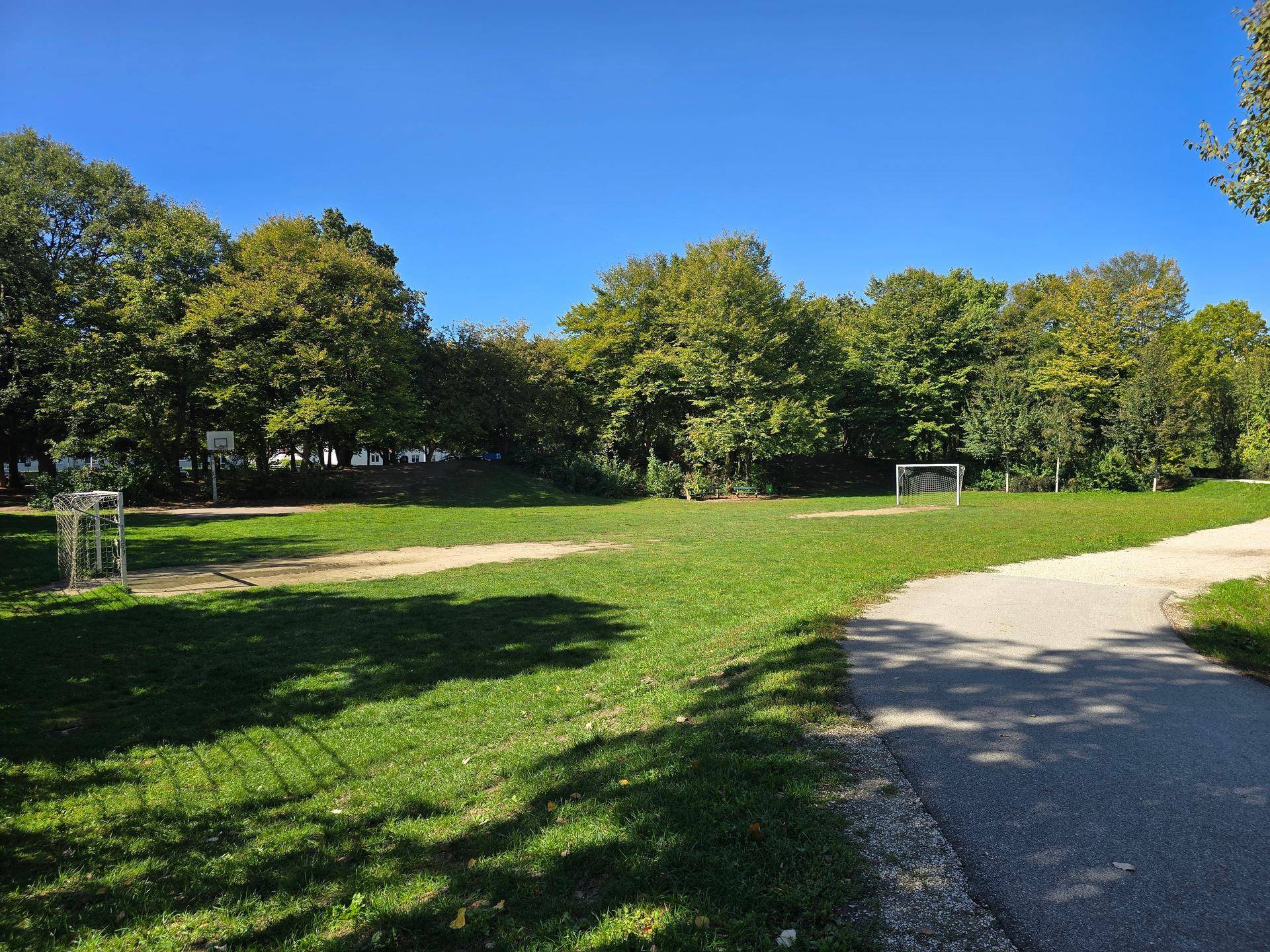 Weitläufige Grünfläche mit Fußballtoren und Basketballkorb, ideal für Sport und Freizeitaktivitäten.