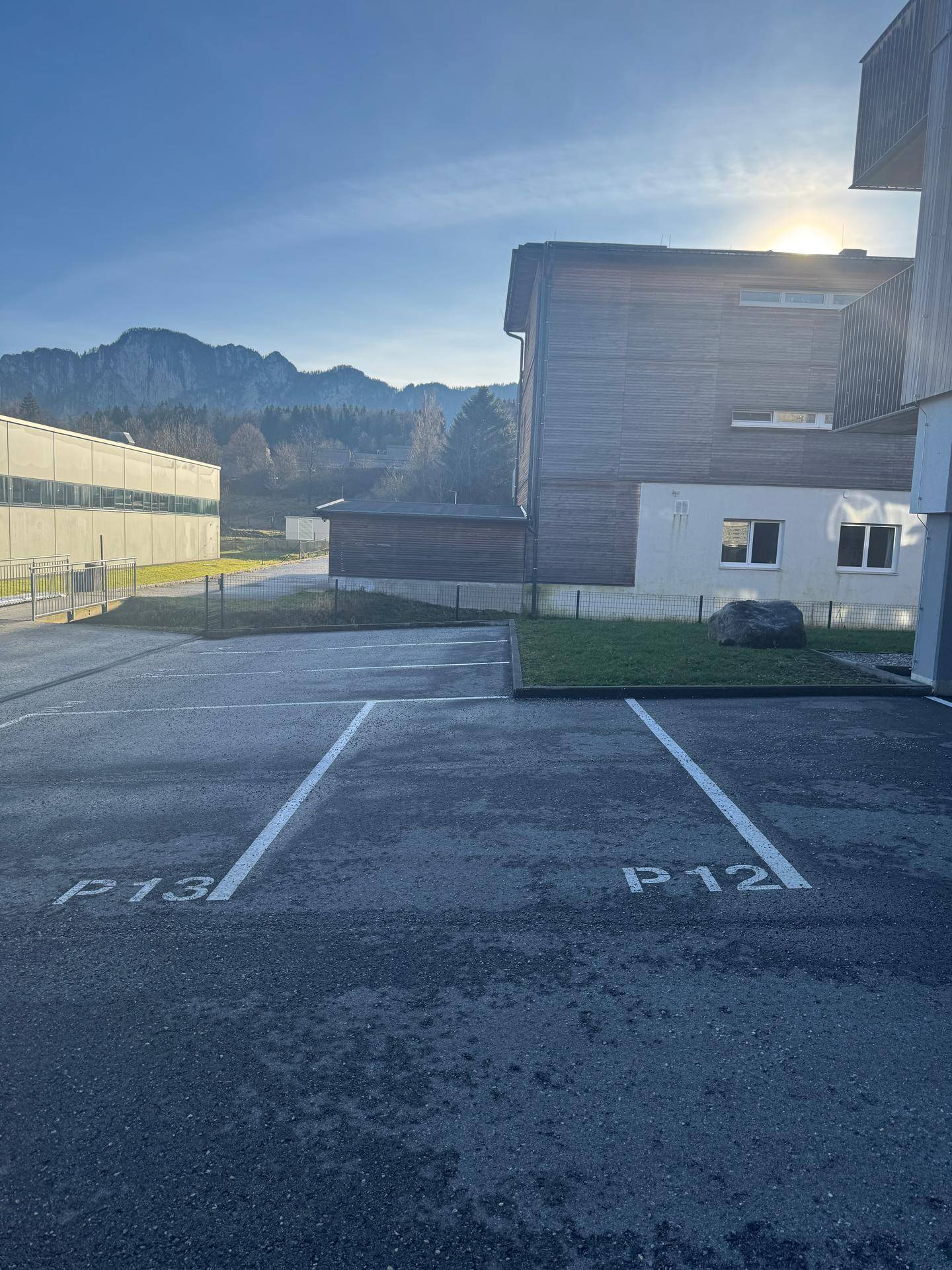 Außenparkplätze mit Blick auf die Berge und moderne Gebäude im Sonnenlicht.