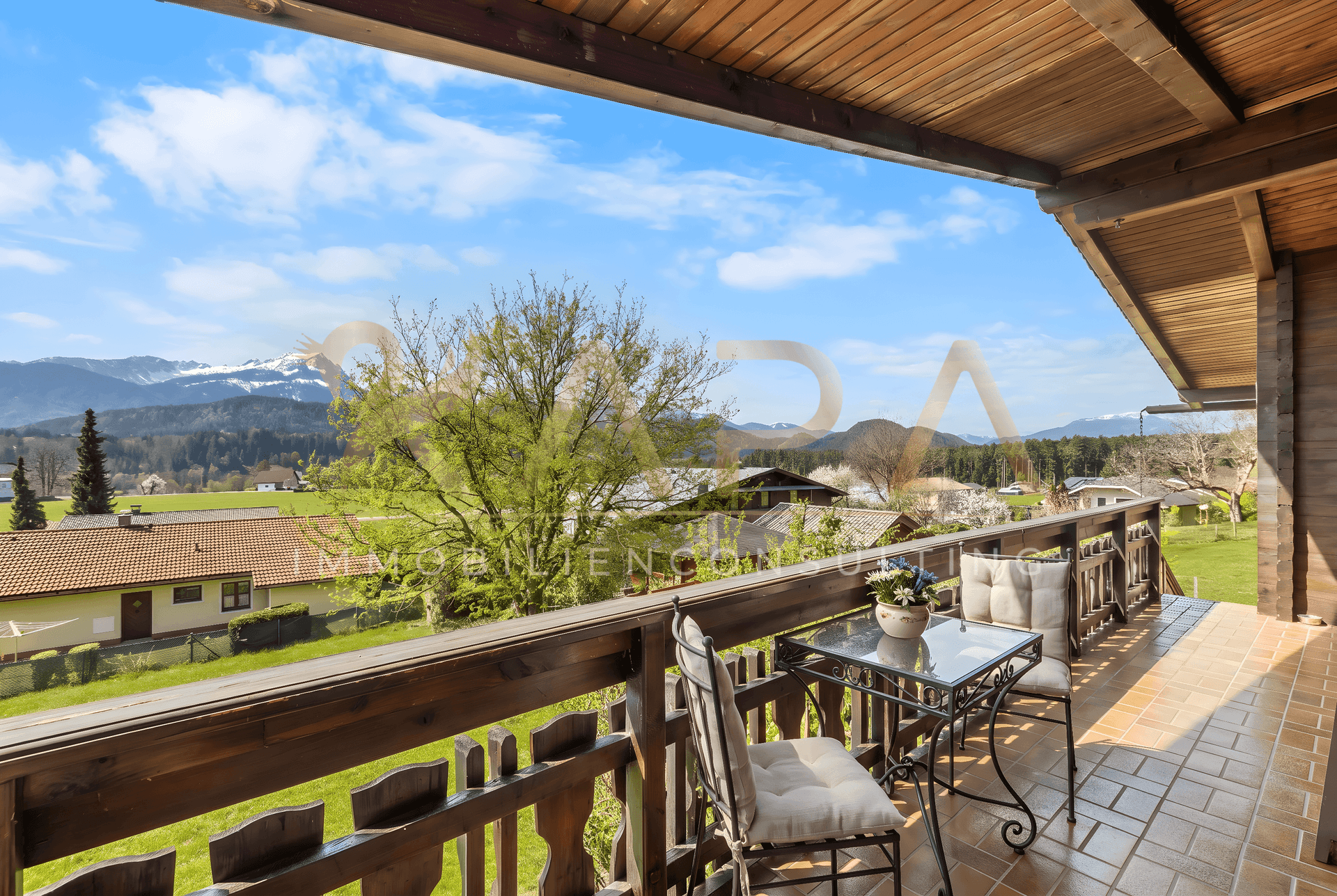 Geräumiger Balkon mit Holzboden und -geländer, möbliert für entspannte Stunden mit Bergblick.