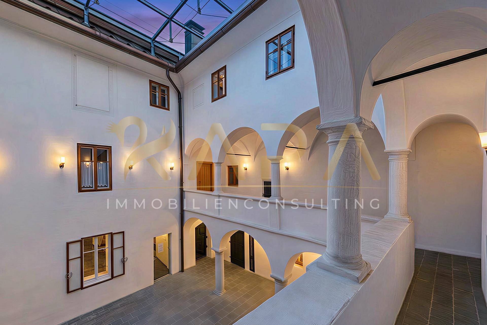 Historischer Innenhof mit Arkaden, Beleuchtung und einem Glasdach, das viel Licht spendet.