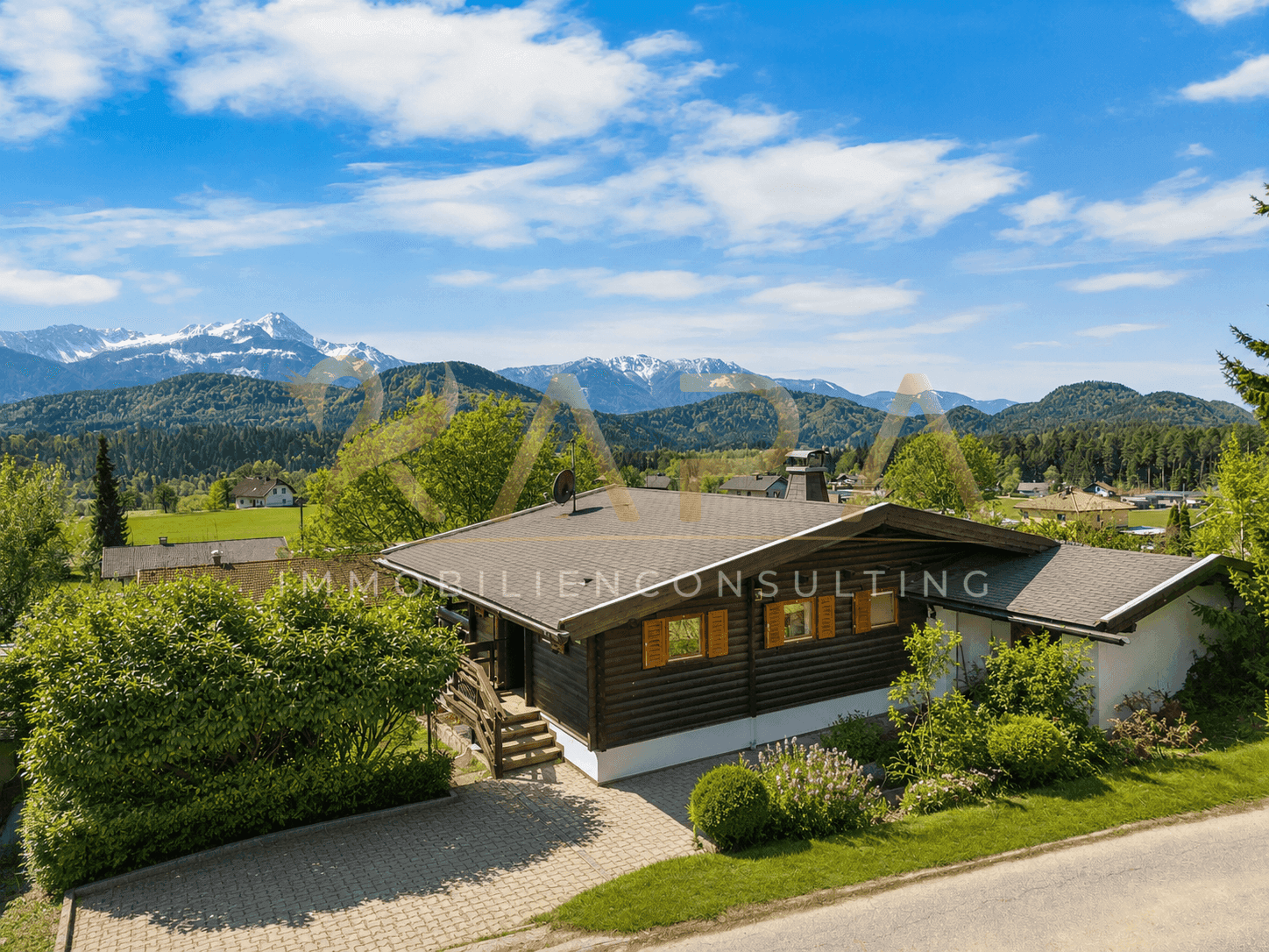 Charmantes Holzhaus mit traditionellen Fensterläden und beeindruckendem Bergblick an einem sonnigen Tag.