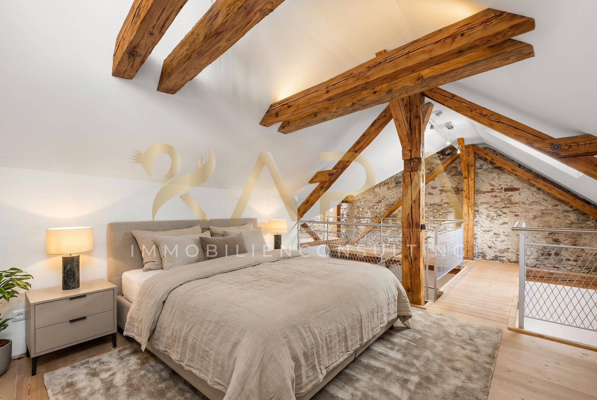 Gemütliches Schlafzimmer im Dachgeschoss mit sichtbaren Holzbalken und Holzboden.
