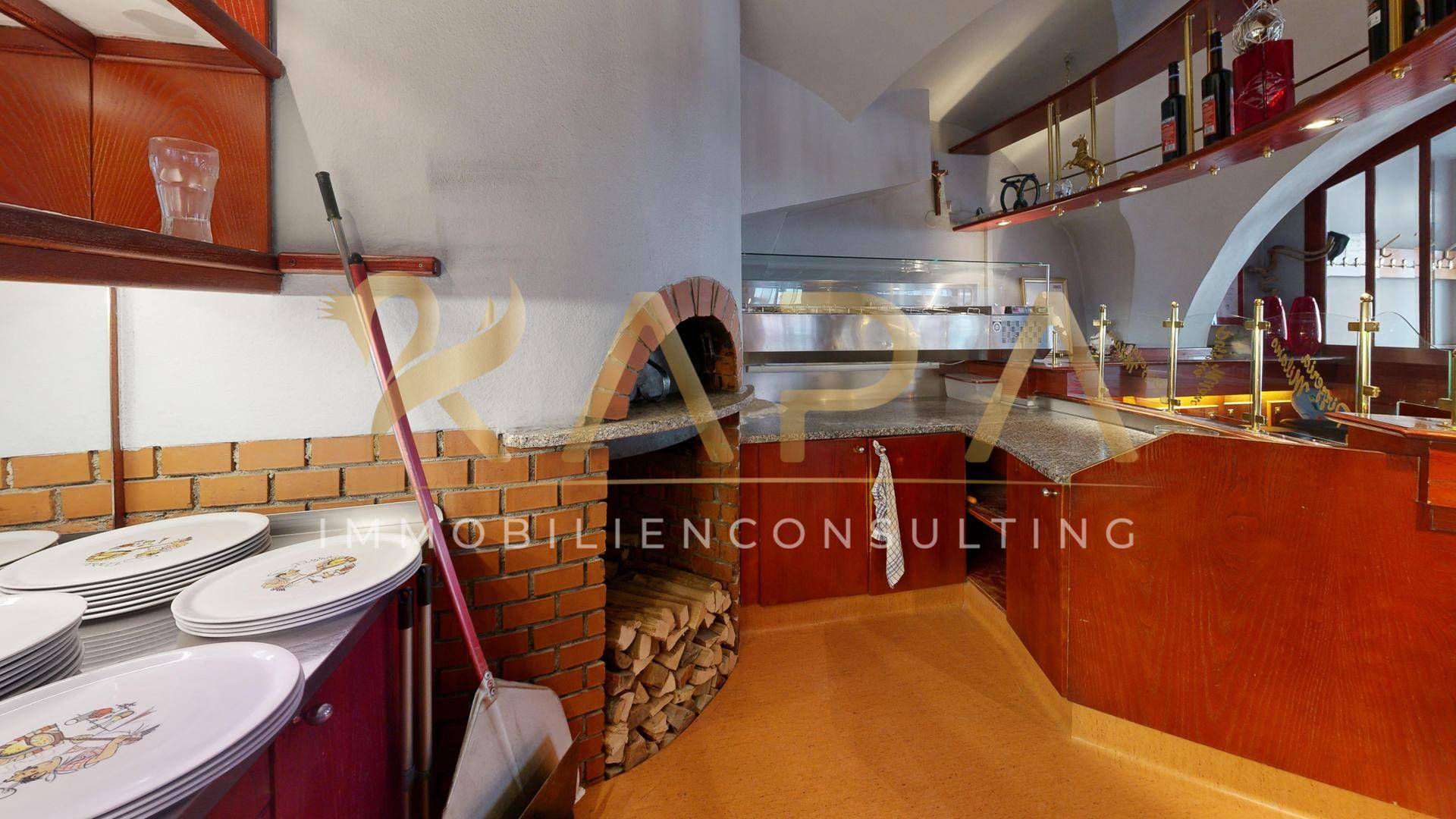 Kommerzielle Küche mit traditionellem Pizzaofen, Holzregalen und Arbeitsflächen.