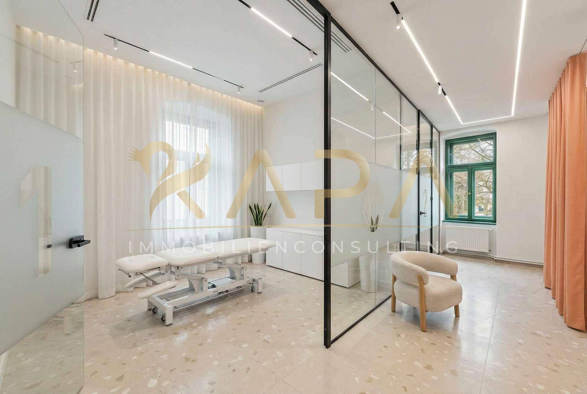 Heller Behandlungsraum mit Glaswänden, Massageliege und modernem Terrazzoboden.