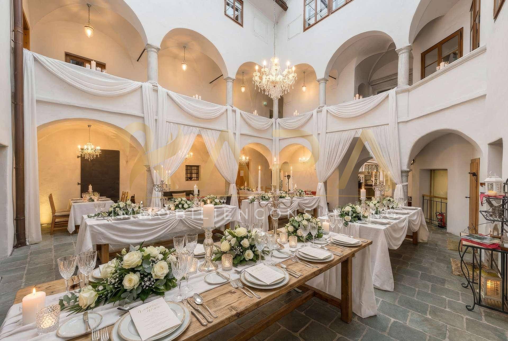 Festlich dekorierter Innenhof mit eleganten Tischen, Bögen und Kronleuchter für Veranstaltungen.