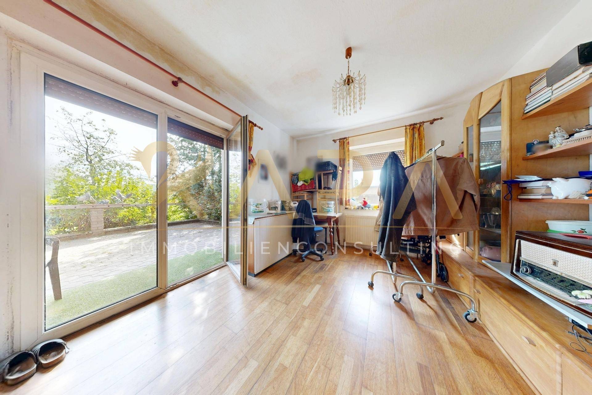 Helles Wohnzimmer mit Holzboden und Zugang zu einer Außenterrasse.