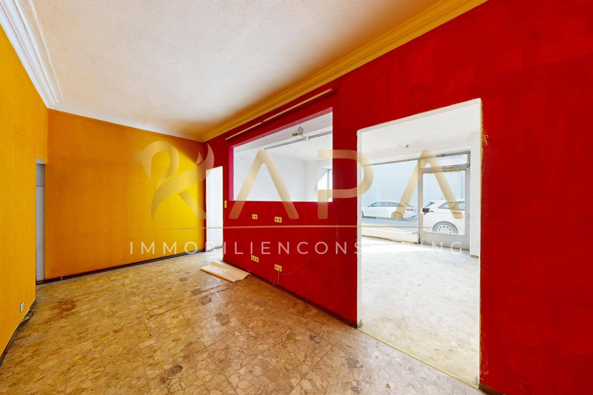 Heller Raum mit auffälligen roten und gelben Wänden und OSB-Plattenboden.