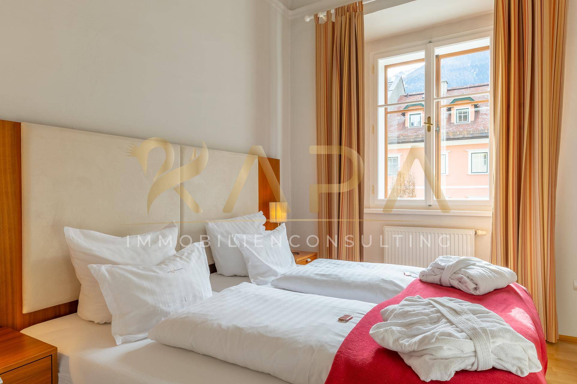 Gemütliches Schlafzimmer mit zwei Einzelbetten, Holzboden und Blick auf die Umgebung.
