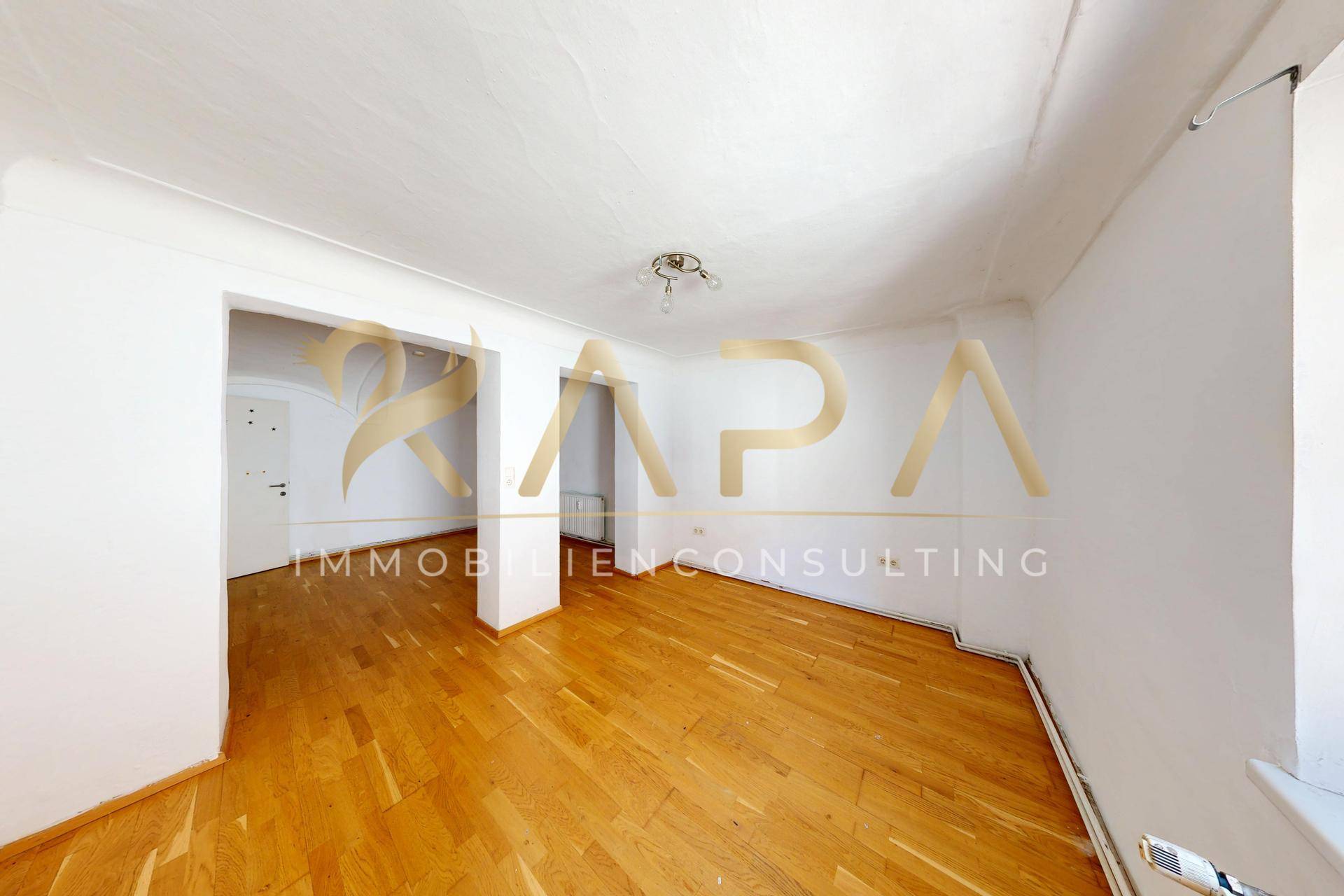 Heller, leerer Raum mit Holzboden und weißen Wänden, bereit zur individuellen Gestaltung.