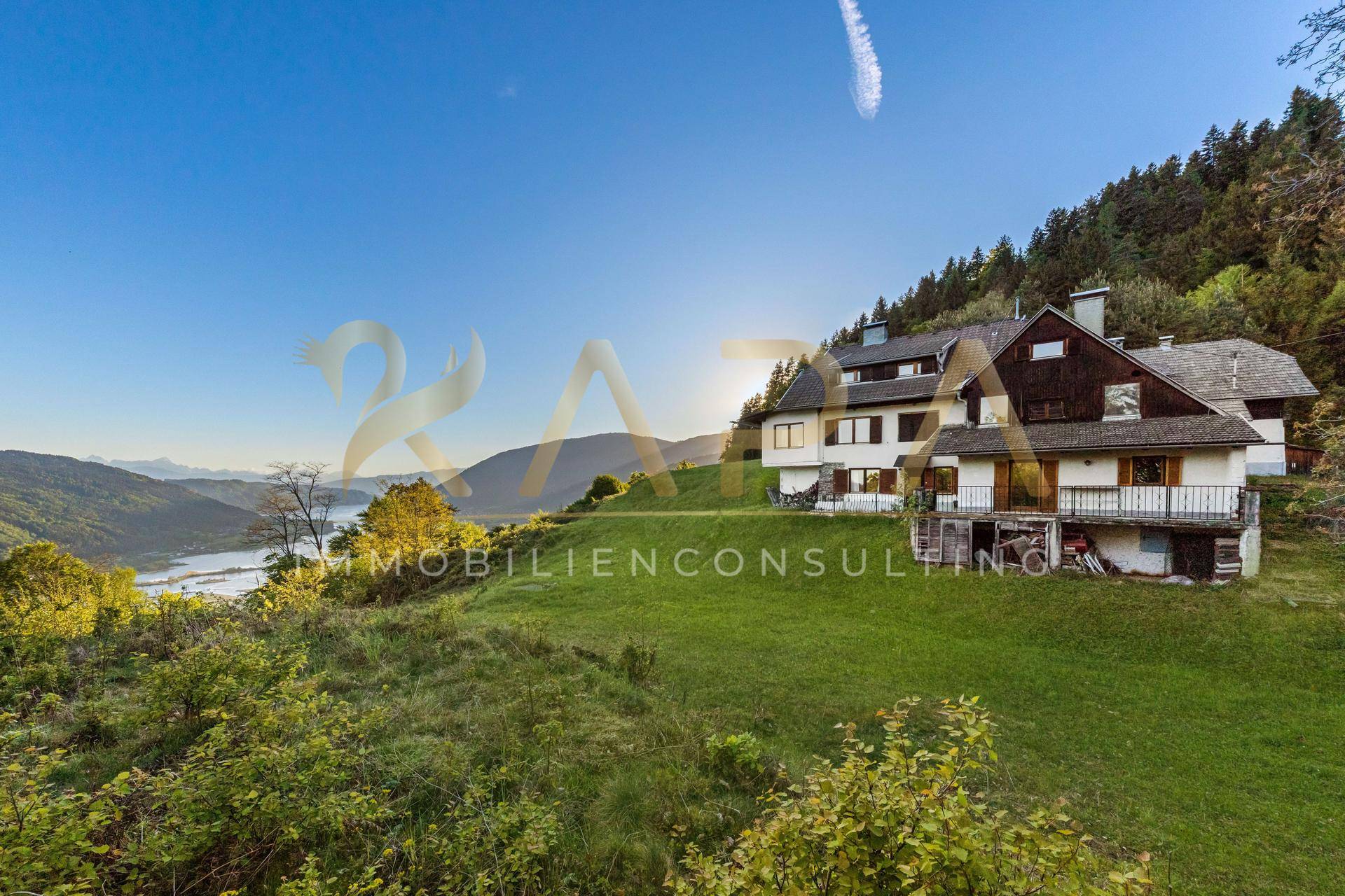 Weitläufige Ansicht des Hauses auf dem Hügel mit Panoramablick auf den See und die Berge.