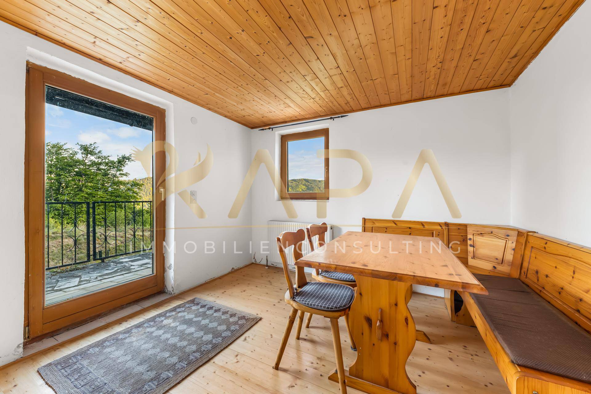 Gemütlicher Essbereich mit Holztisch, Eckbank und Zugang zu einem kleinen Balkon.