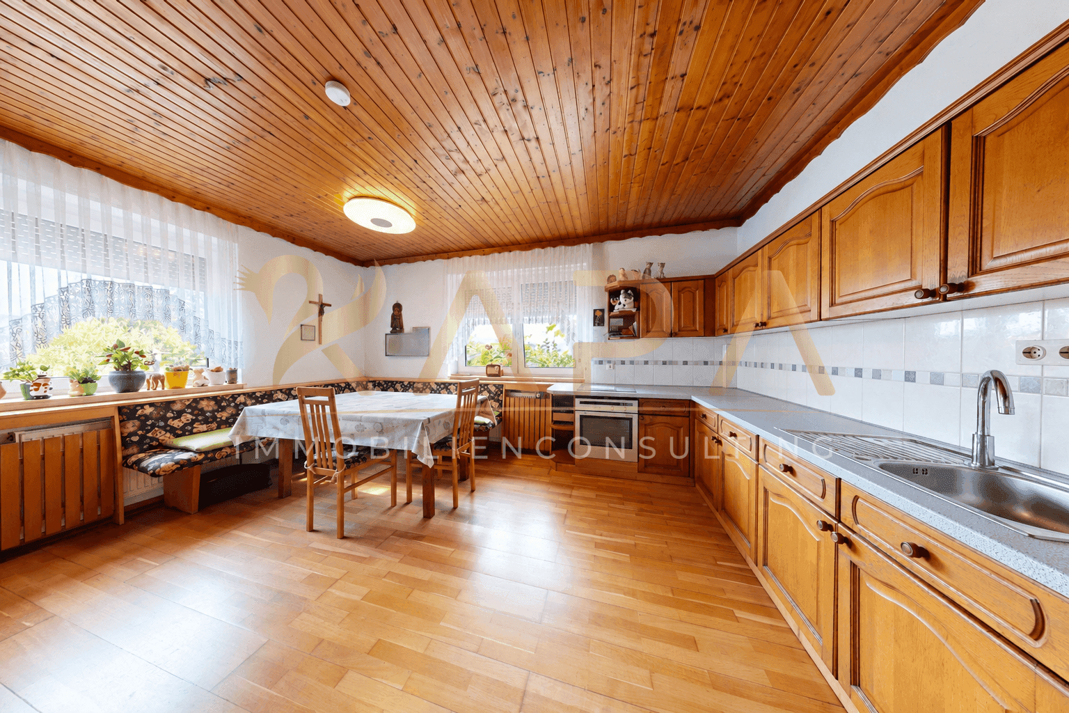 Geräumige Wohnküche mit Holzeinbauten, Essbereich und Holzdecke.