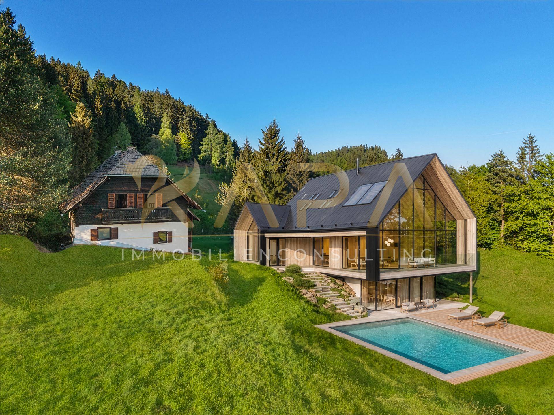 Moderne Villa mit Glasfassade und traditionellem Chalet, umgeben von Natur mit Pool und Liegewiese.