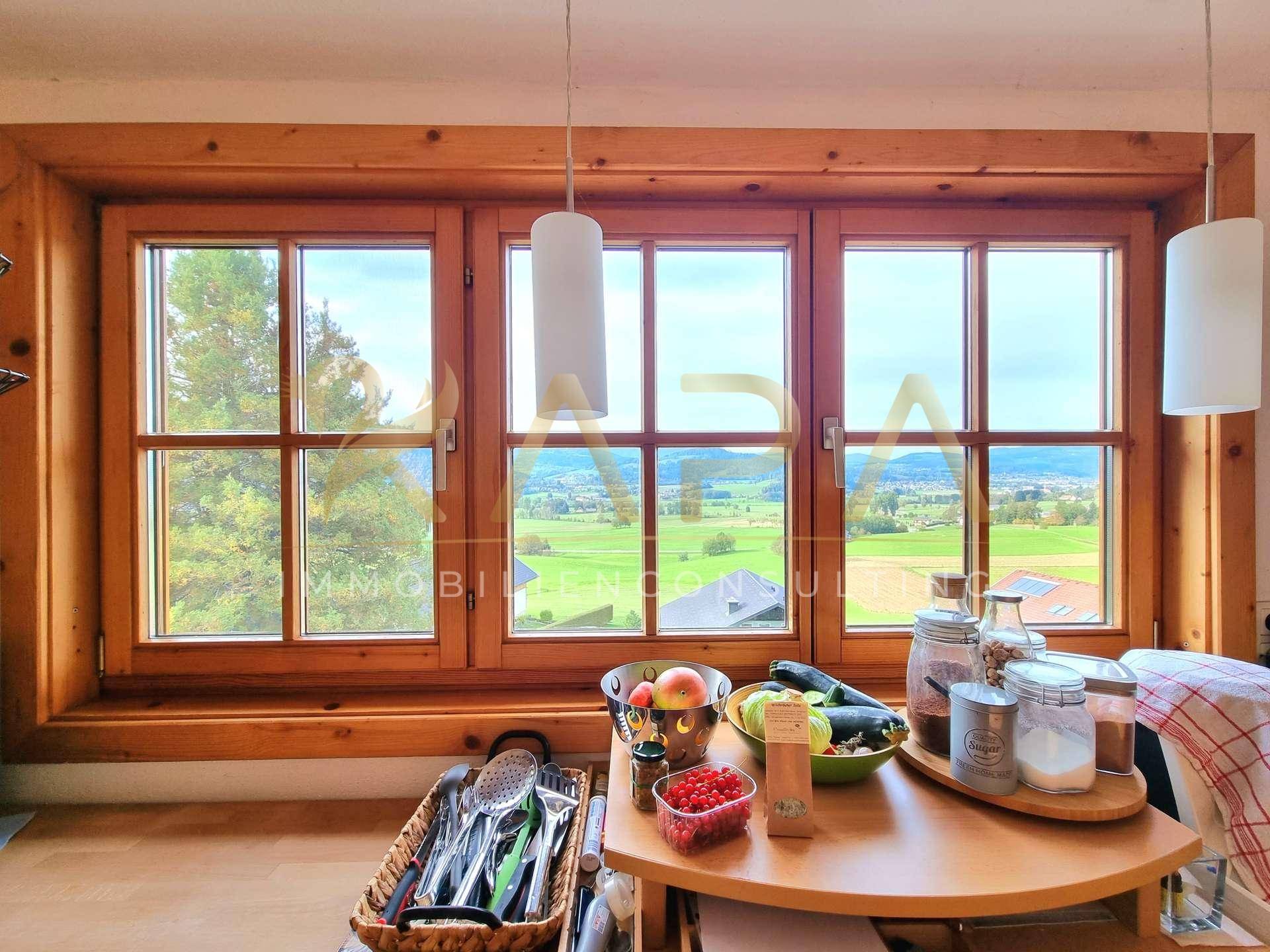 Helle Küche mit Holzfenstern und weitem Blick über die grüne Landschaft und die Umgebung.